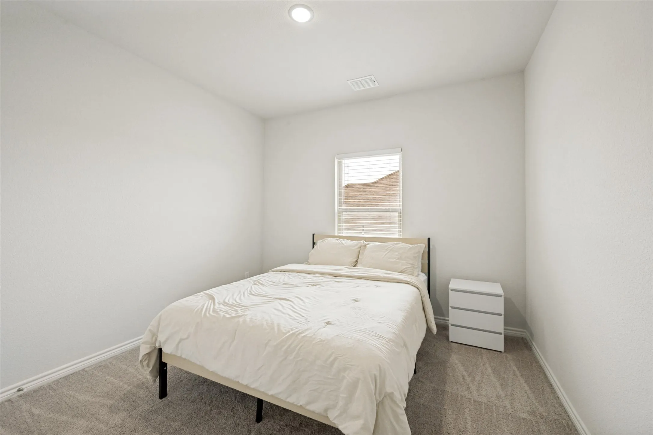 Neutral color palette room featuring light-colored textured walls and gray patterned carpeting