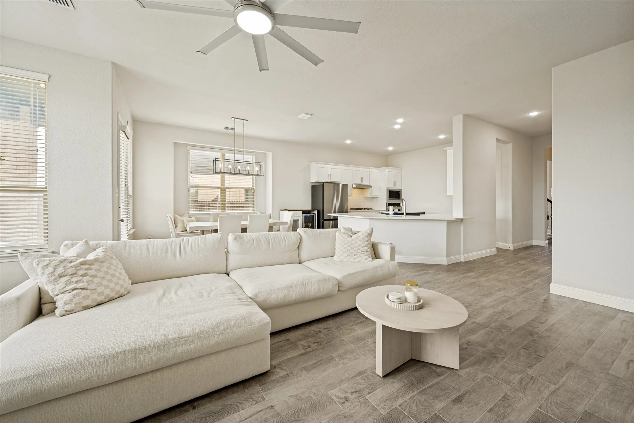 Open-concept living space featuring wood-finish flooring, recessed lighting, and a contemporary ceiling fan