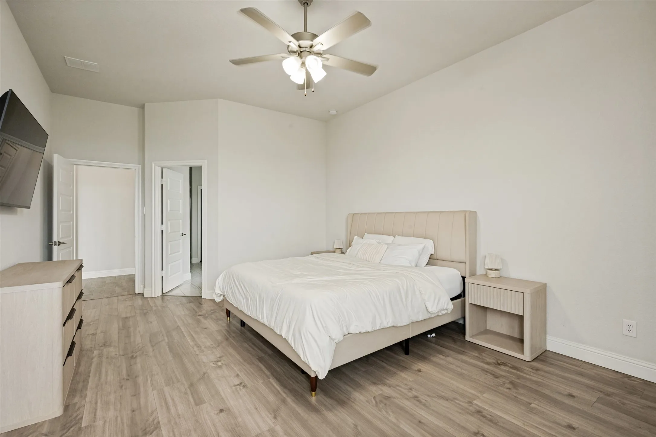 Spacious room featuring wood-finish flooring, vaulted ceilings, and a ceiling fan with integrated lighting