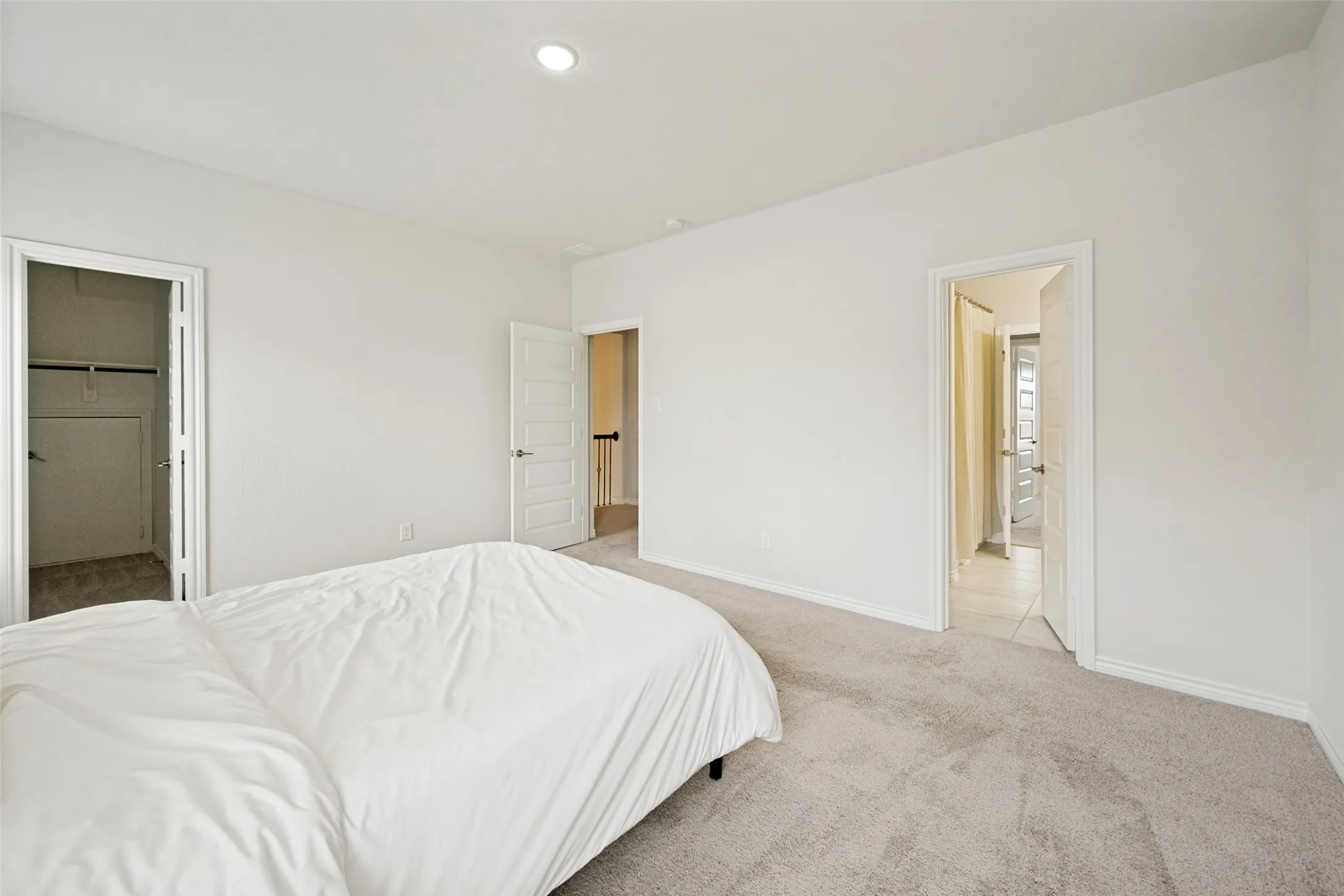 Carpeted bedroom with recessed lighting, white walls, and a closet featuring wire shelving