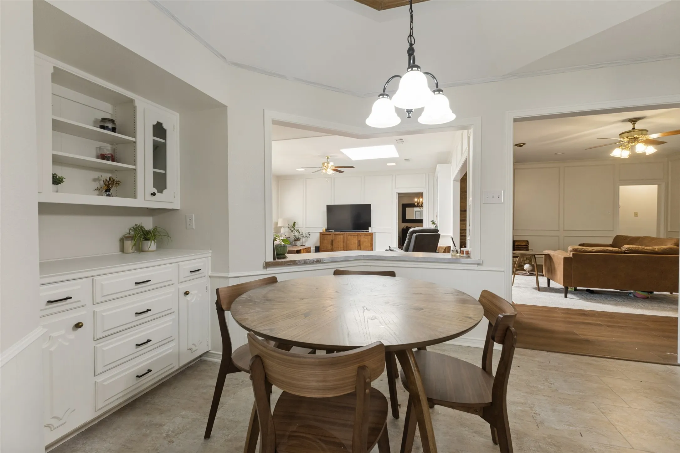 Dining area featuring a contemporary chandelier, built-in cabinetry, and a pass-through window to an additional living space