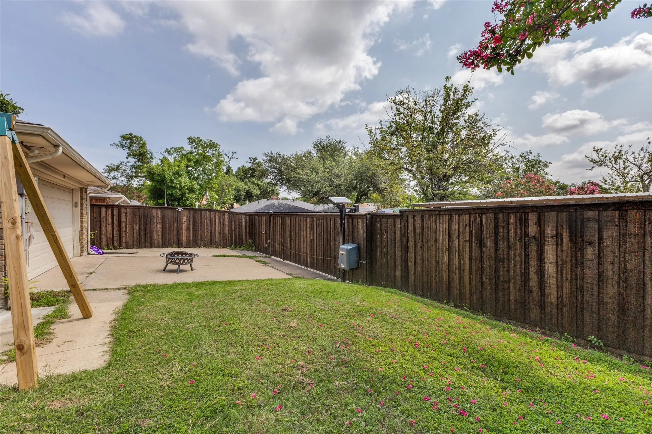 Private backyard featuring a concrete patio, fenced perimeter, and a sloped grassy area
