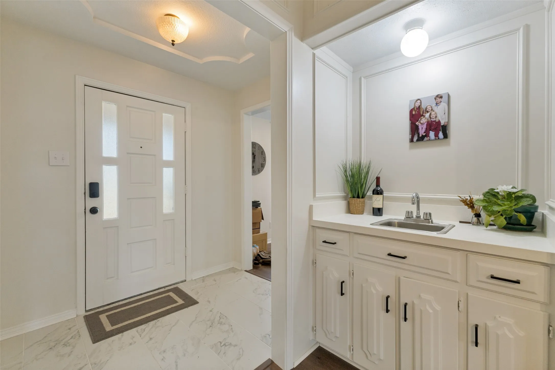 Entryway featuring a decorative front door with frosted glass panels, an overhead light fixture, and marble-look tile flooring