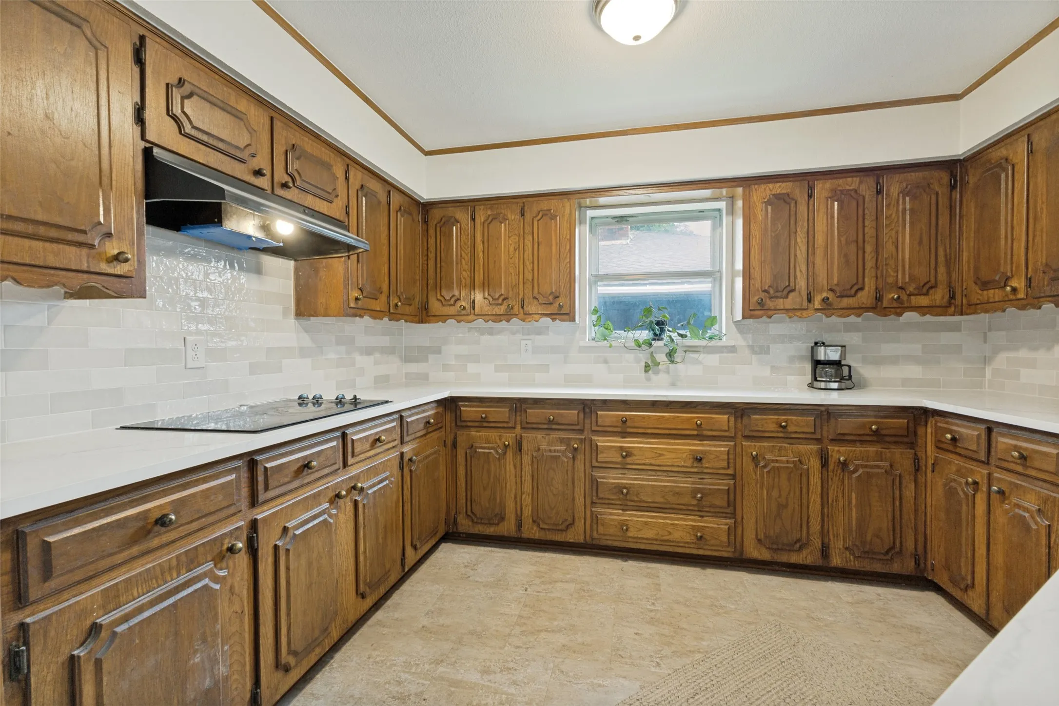 U-shaped kitchen featuring wood cabinetry, light-toned countertops, and a white subway tile backsplash