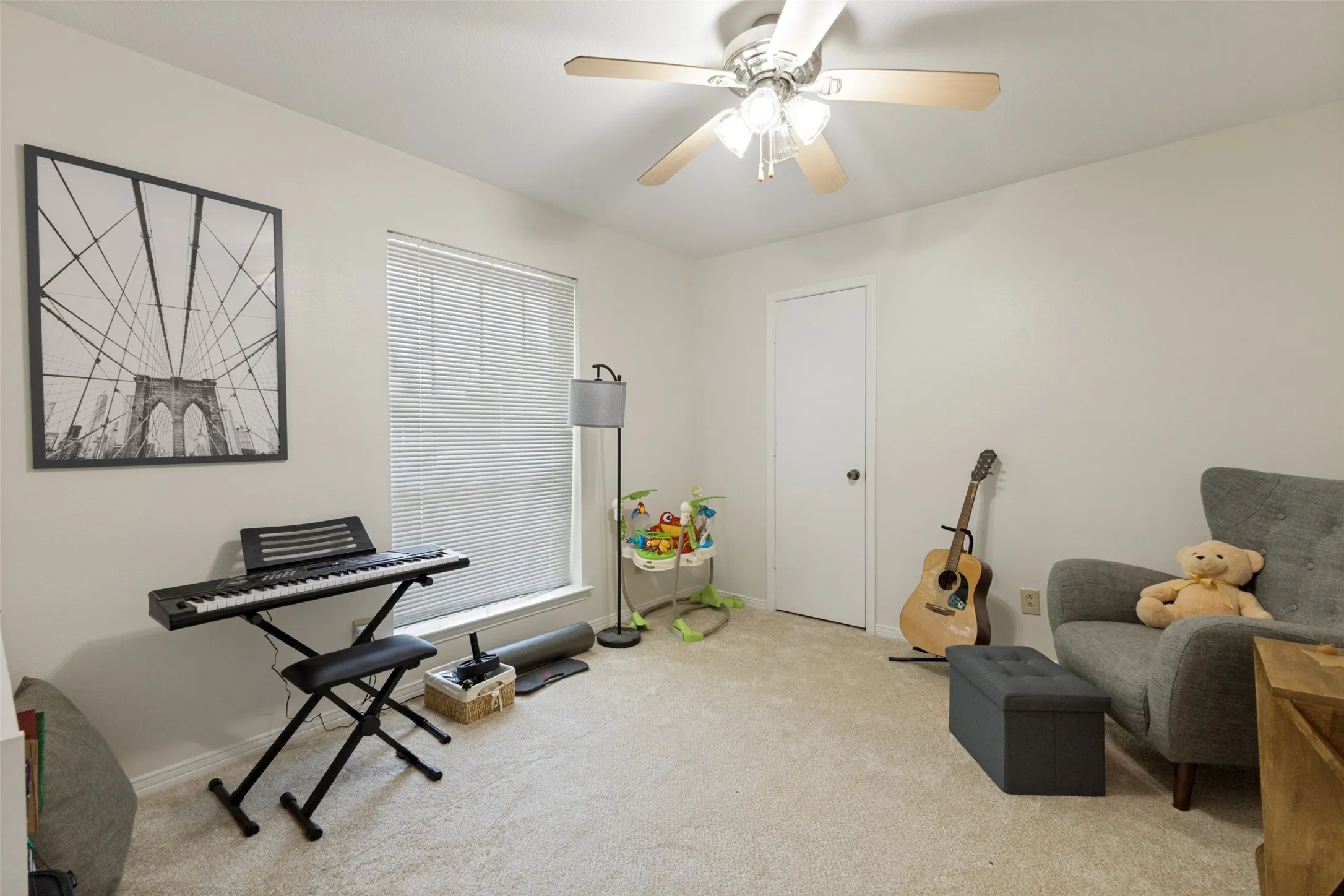 Carpeted room featuring a ceiling fan with light fixture, a window with blinds, and white walls