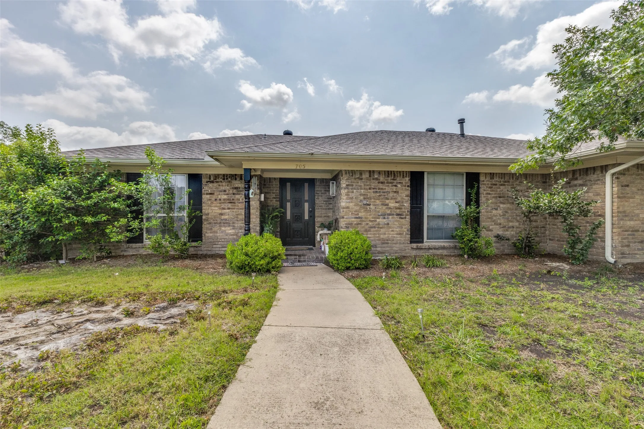 Brick facade residence with a gabled roof and a concrete walkway