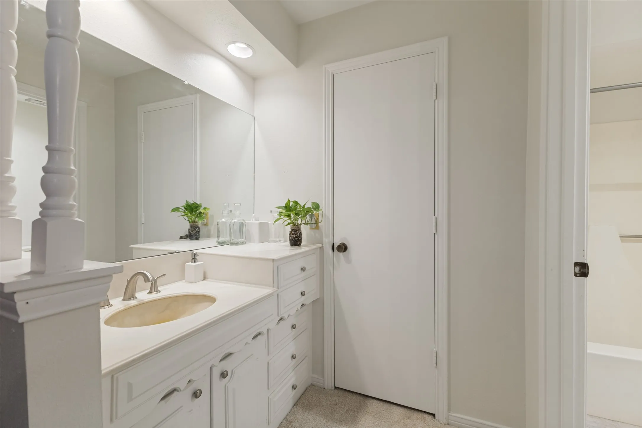 Bathroom vanity with an integrated oval sink, brushed nickel faucet, and white cabinetry featuring decorative hardware