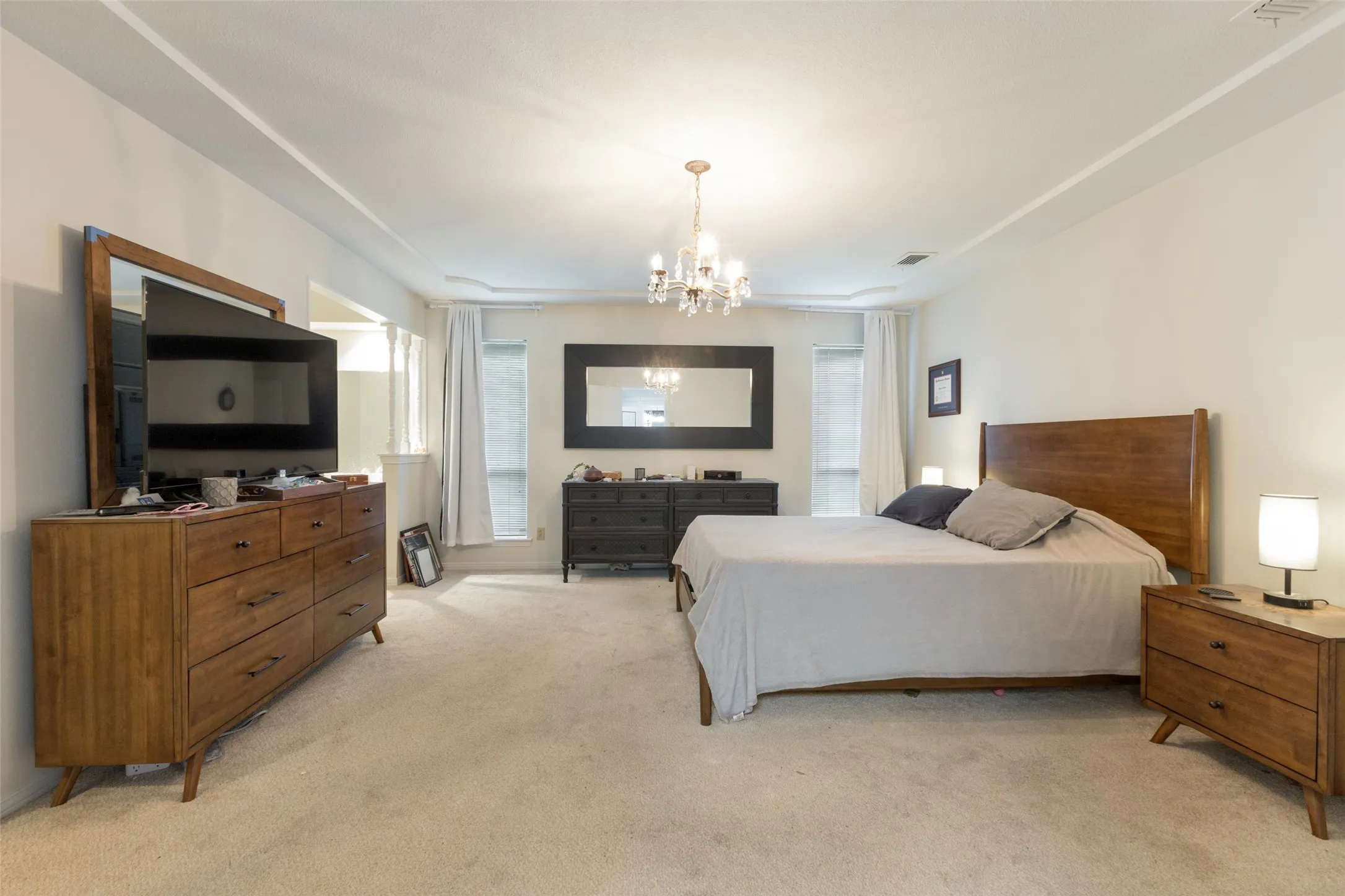 Broadloom carpeted room featuring a tray ceiling with a crystal chandelier