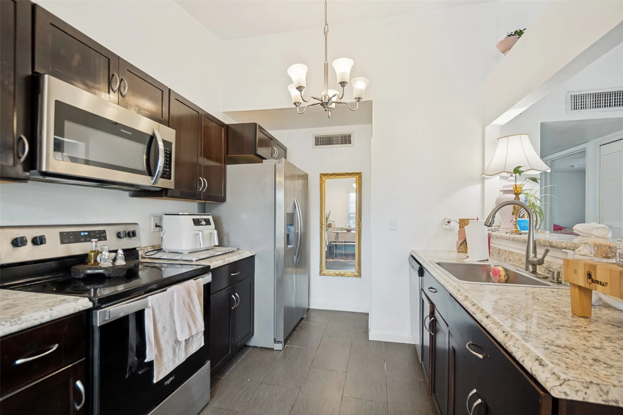 Kitchen featuring dark wood cabinetry, light-toned countertops, stainless steel appliances, and wood-finish flooring