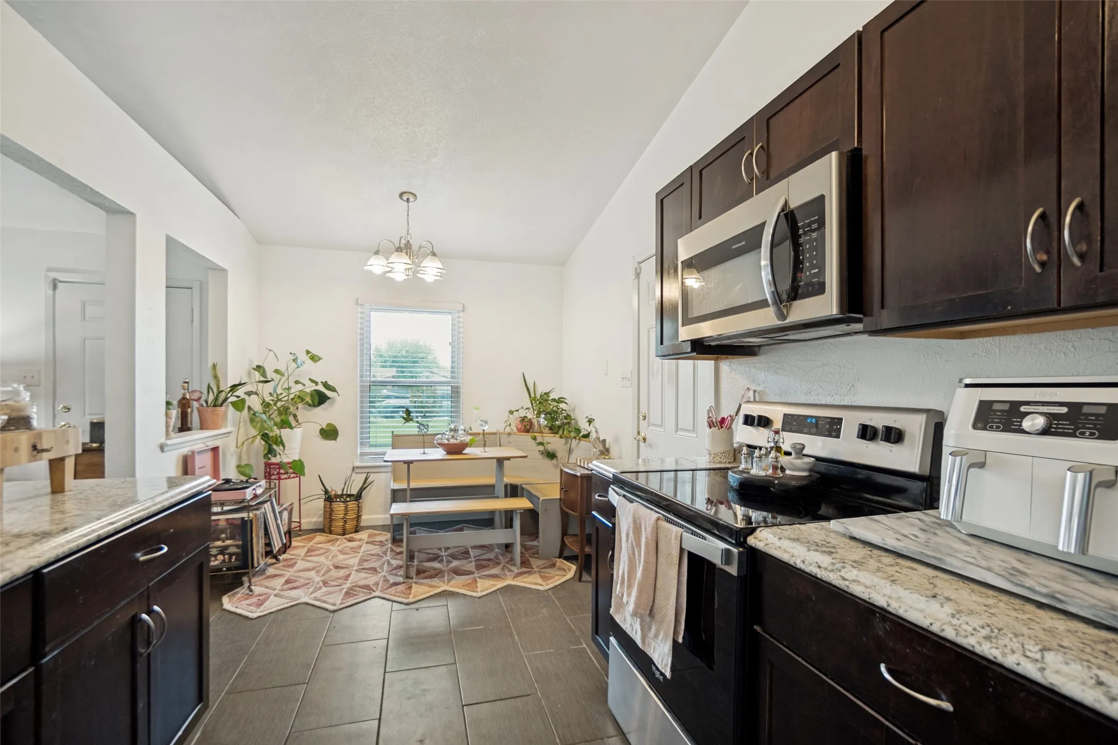 Kitchen featuring dark wood cabinetry, light-toned countertops, and dark tile flooring
