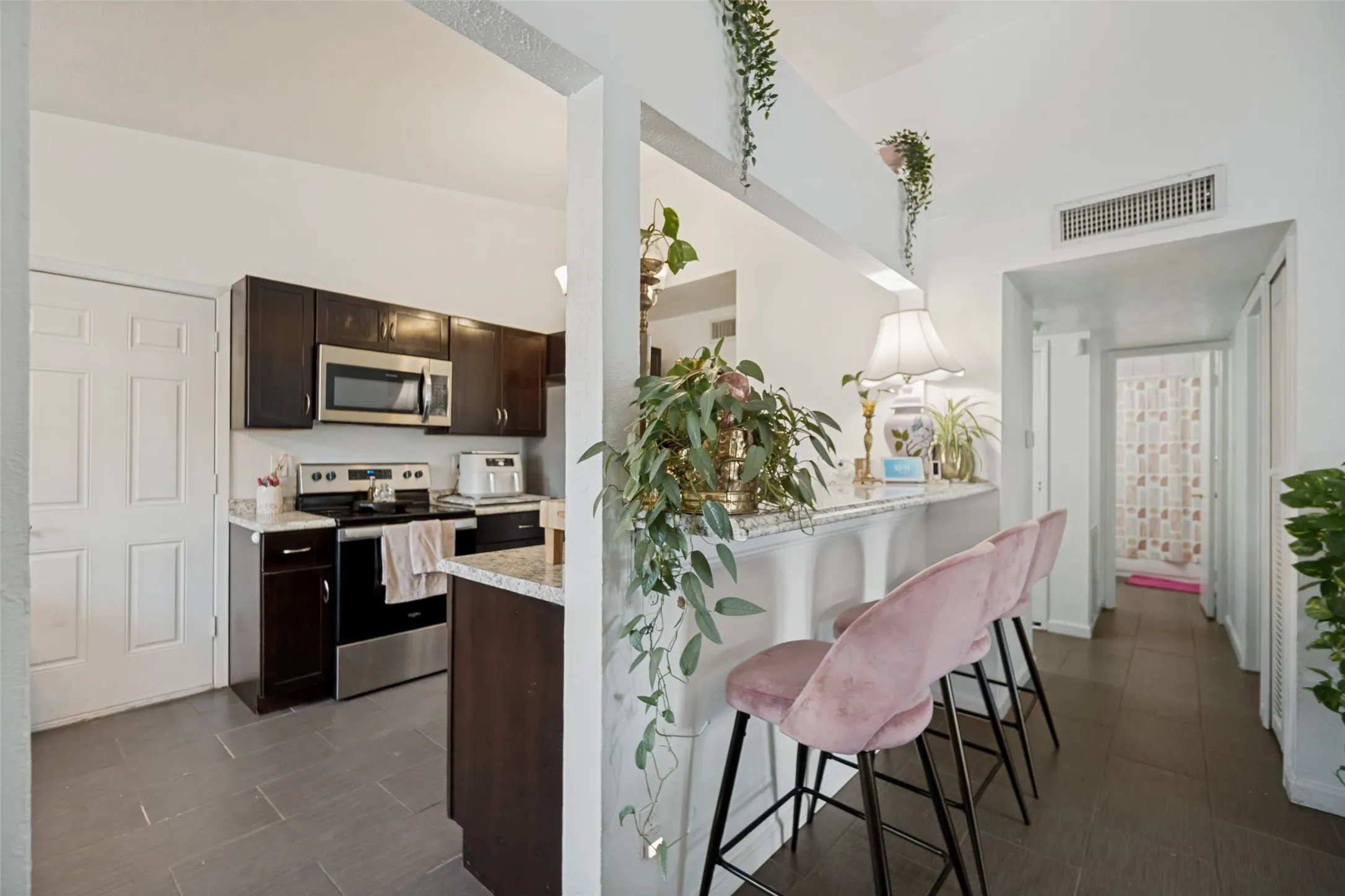 Kitchen area featuring dark wood-finish cabinetry, stainless steel appliances, and a light-toned countertop