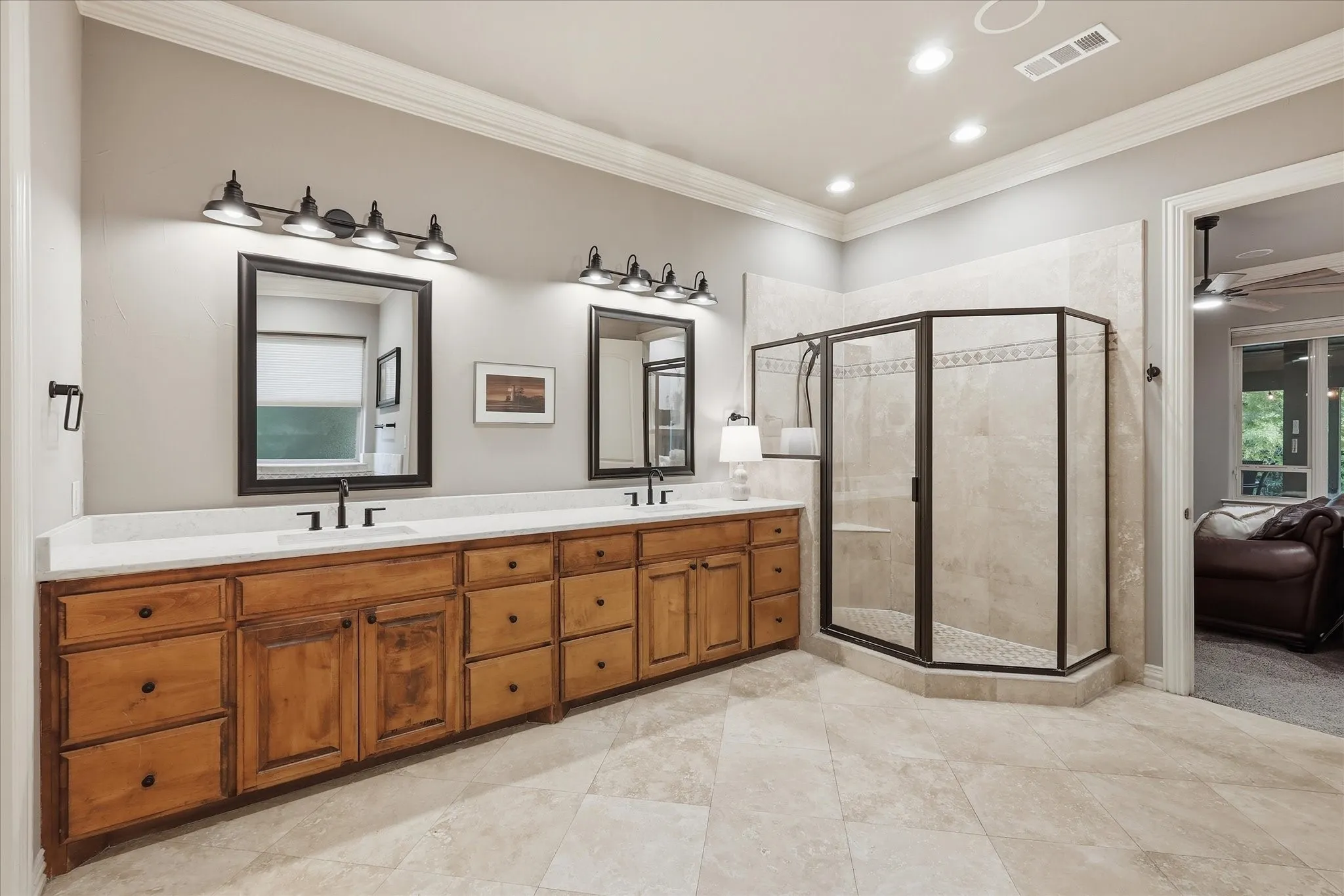 The primary ensuite bath is the epitome of luxury with double crown molding, Turkish travertine floors, a 10' long double sink custom knotty alder vanity, new quartz countertop, sinks, mirrors, lighting and fixtures.