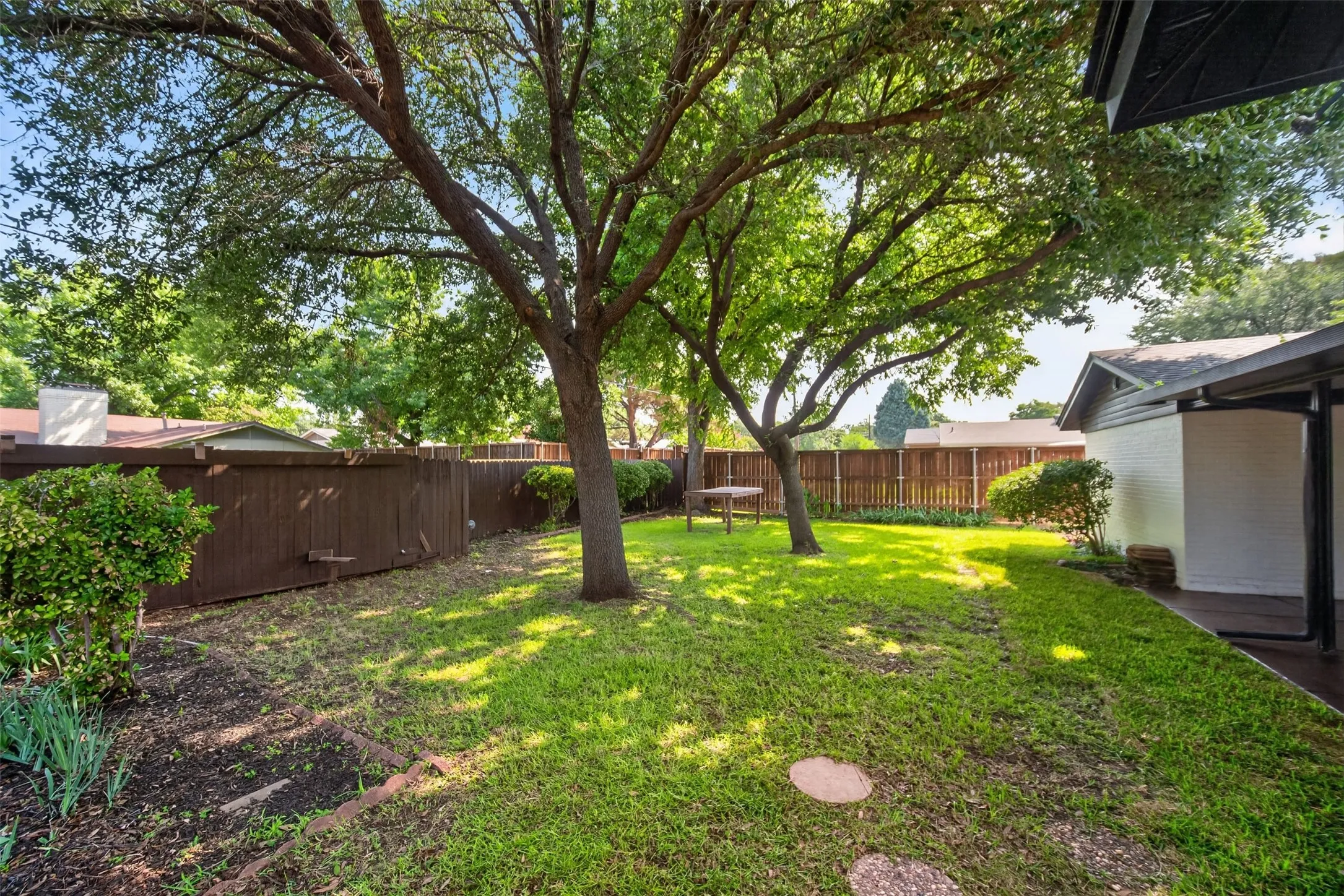 Spacious backyard featuring established trees, a grassy lawn, and a privacy fence