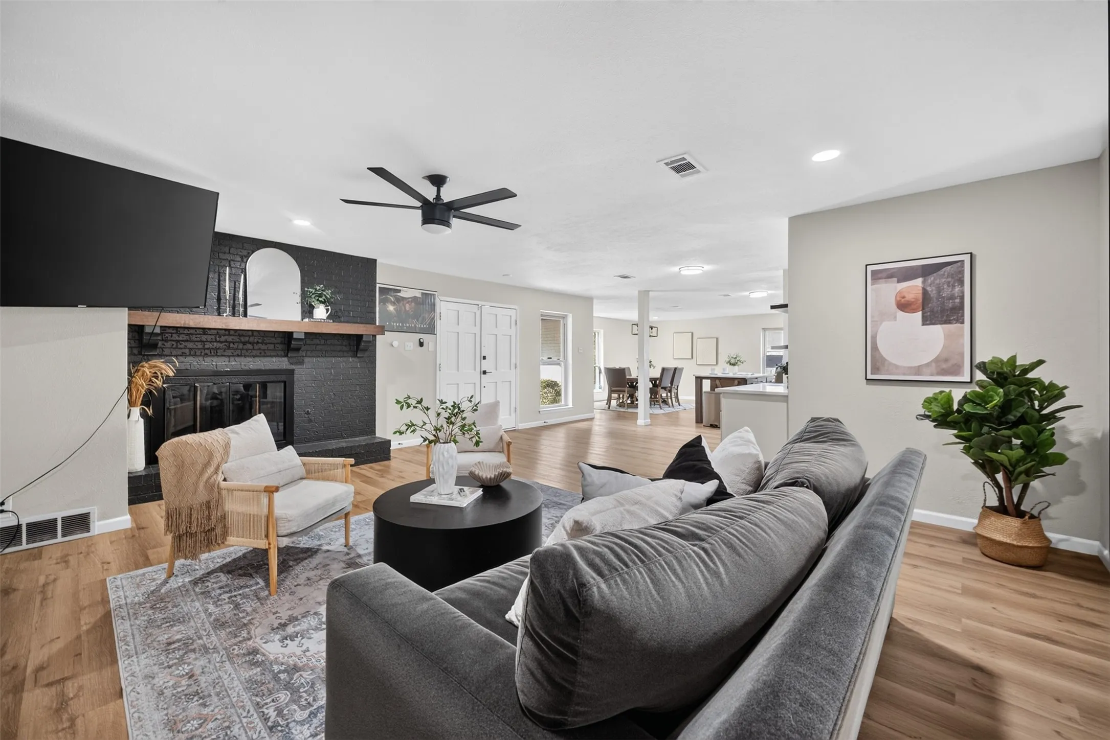 Spacious living area featuring wood-finish flooring and a black brick fireplace with a wood mantle