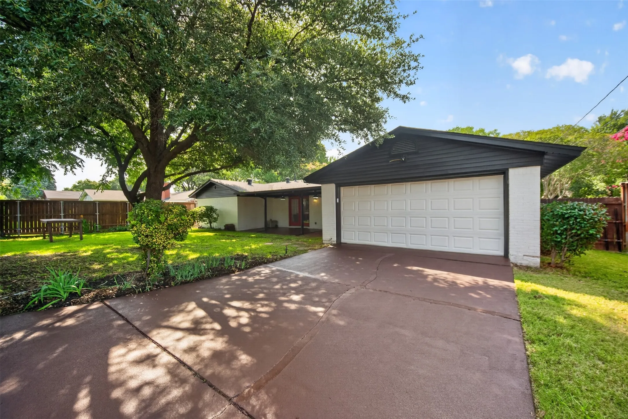 Front exterior with a two-car garage, white brick facade, and a dark brown driveway