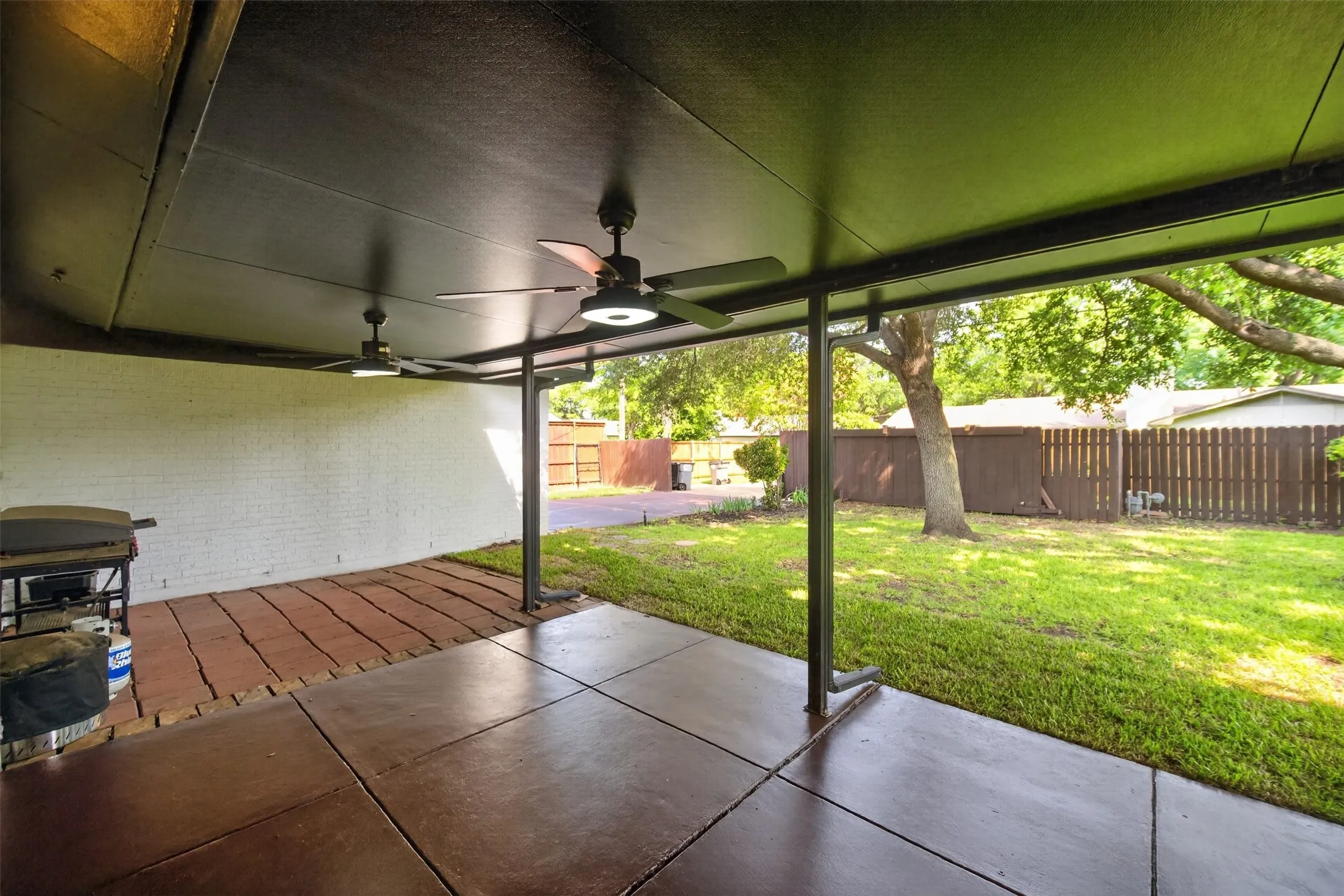 Covered patio with concrete flooring, accented by a brick paver section