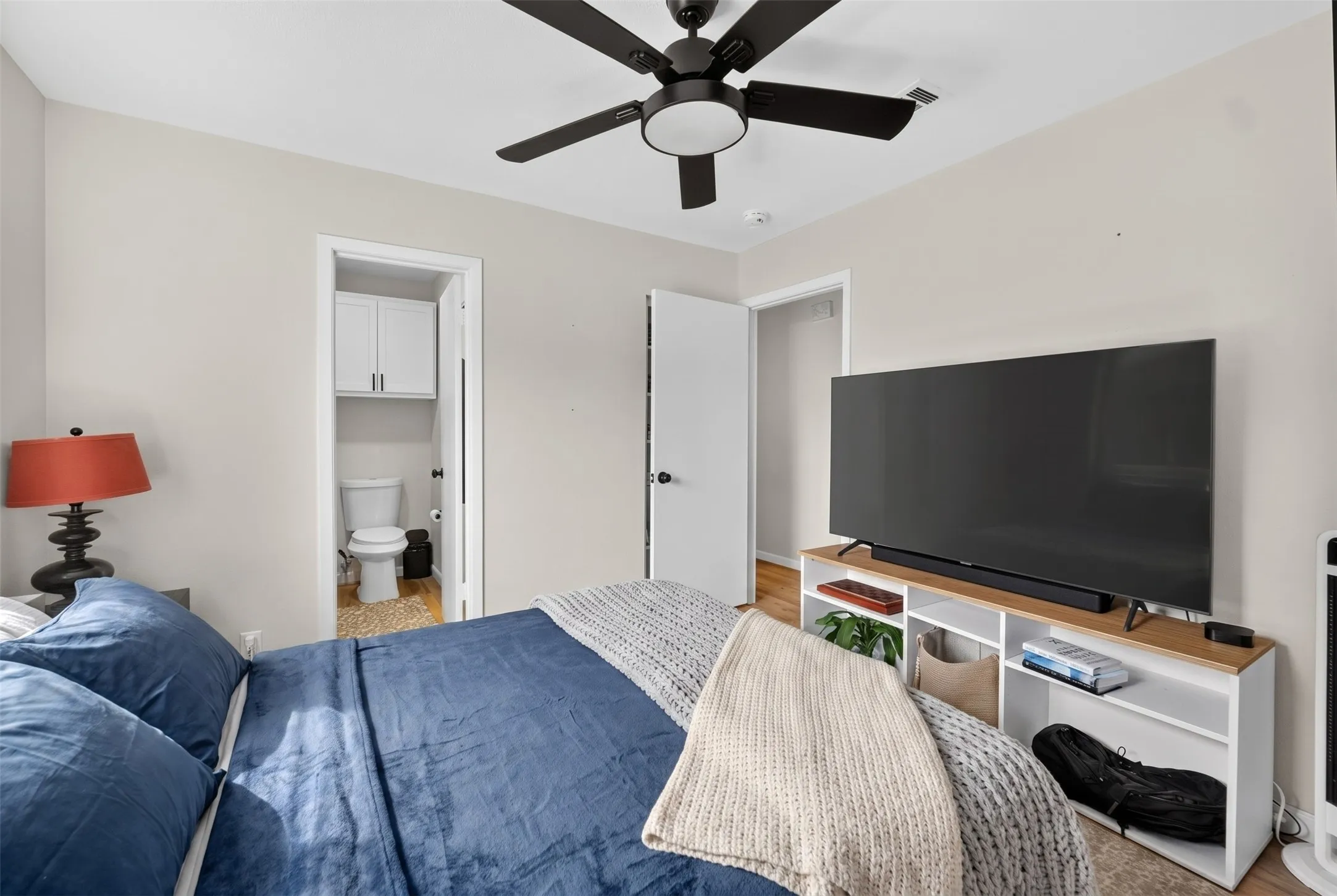 Bedroom featuring light neutral wall paint, a black ceiling fan, and wood-finish flooring