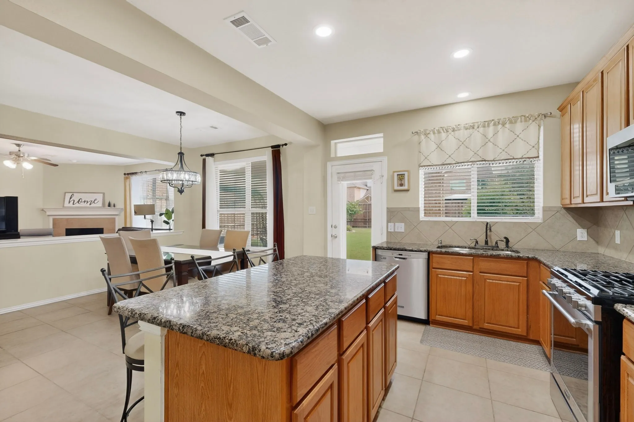 Kitchen featuring a granite-topped island, light wood cabinetry, and stainless steel appliances