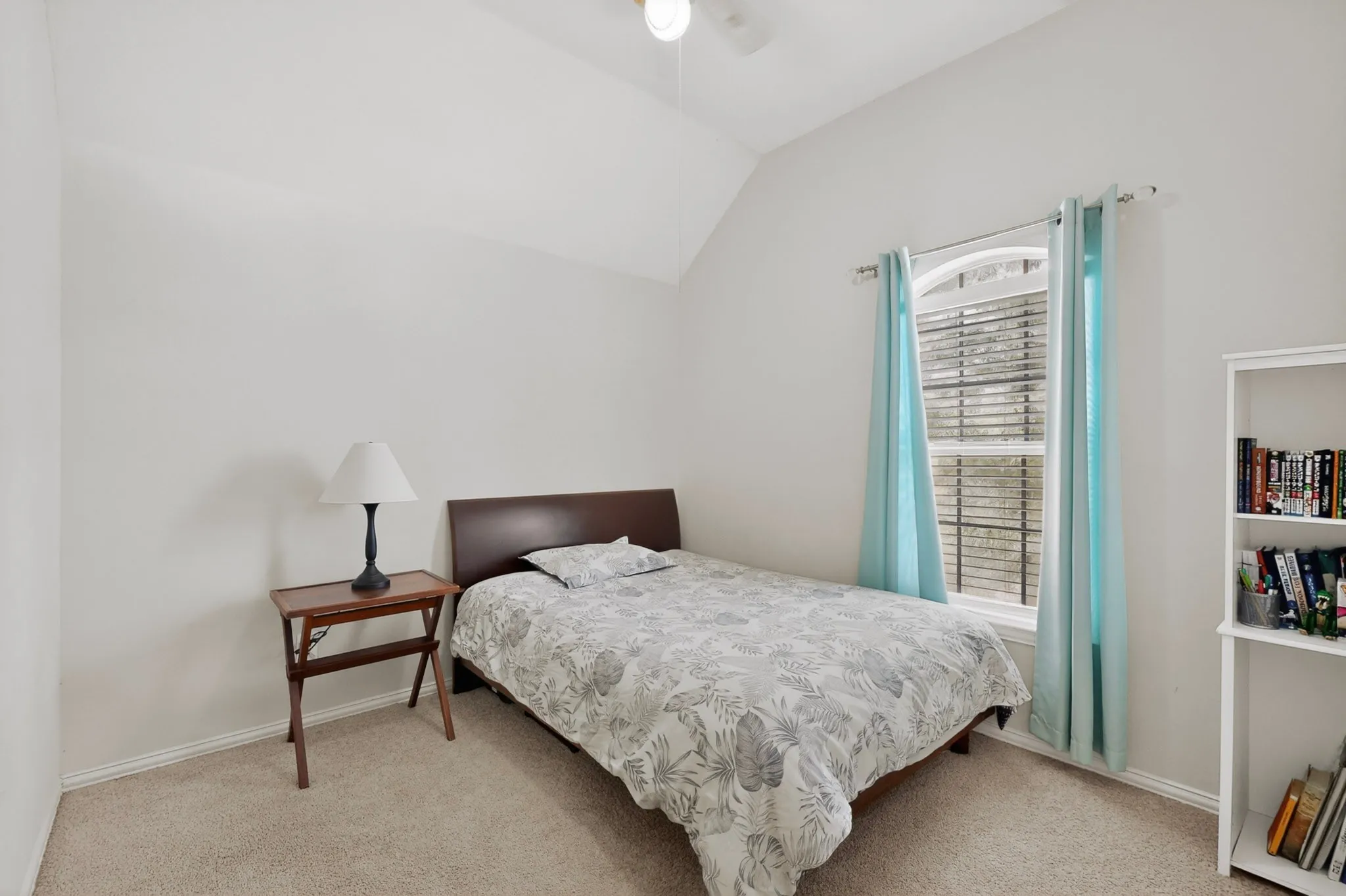 Carpeted room featuring a vaulted ceiling and a window with blinds