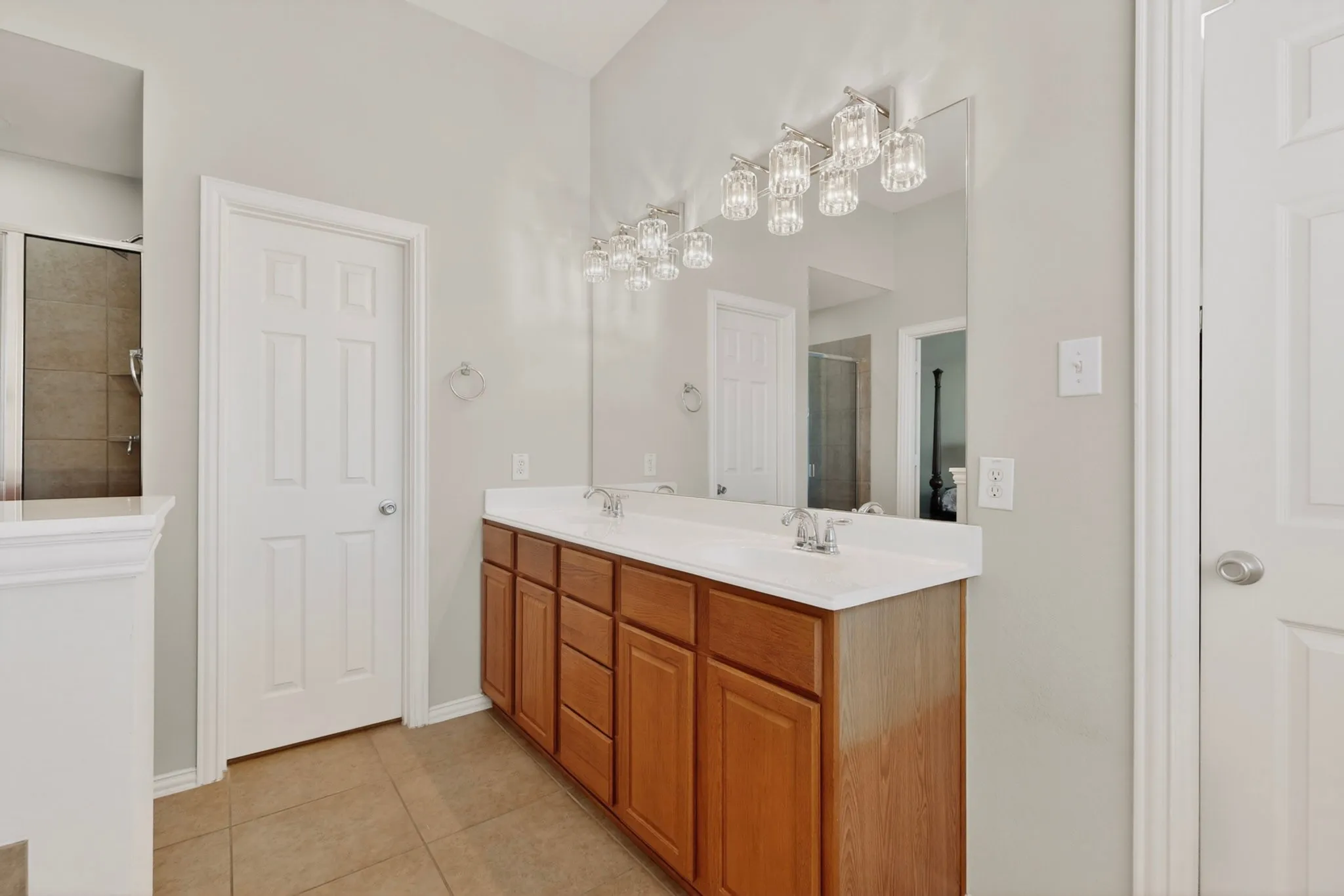 Dual sink vanity with wood-finish cabinetry, white countertops, and chrome fixtures