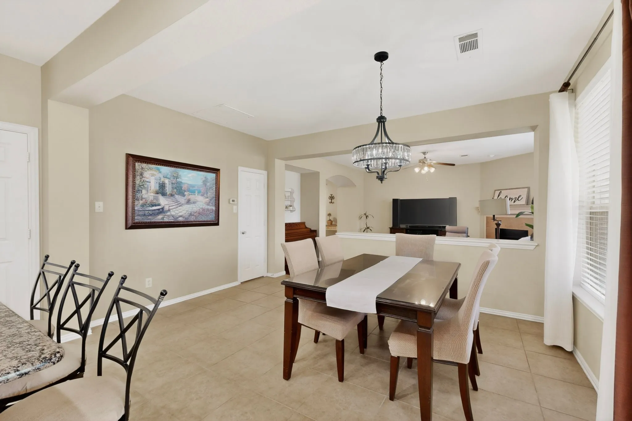 Dining area featuring neutral wall tones, tile flooring, a decorative chandelier, and an architectural half-wall partition