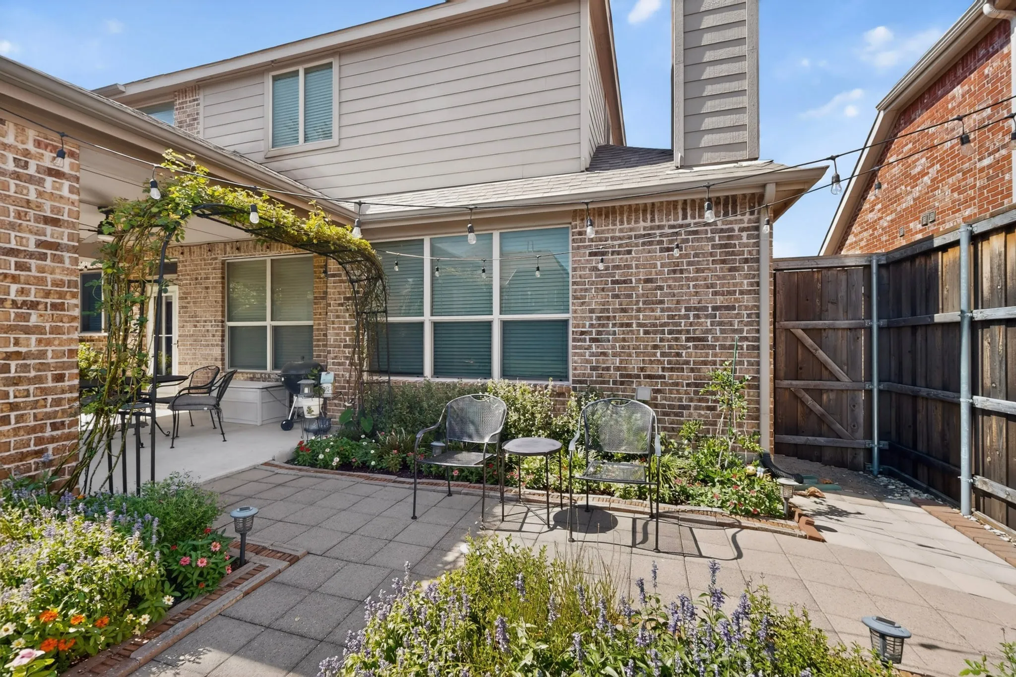 Expansive brick exterior featuring an arched pergola with established climbing vines