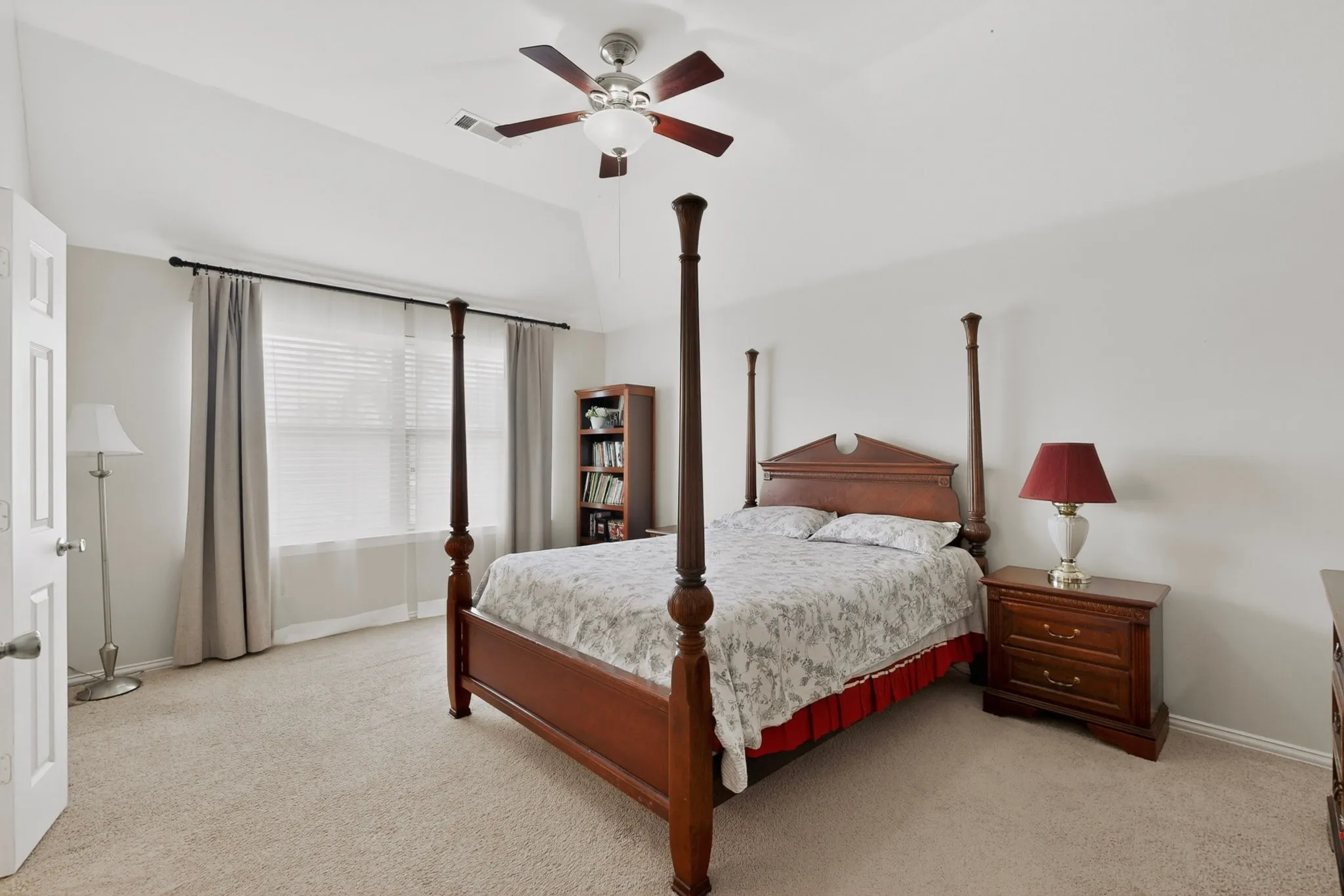 Spacious bedroom featuring vaulted ceilings, a ceiling fan with integrated lighting, and neutral carpeting