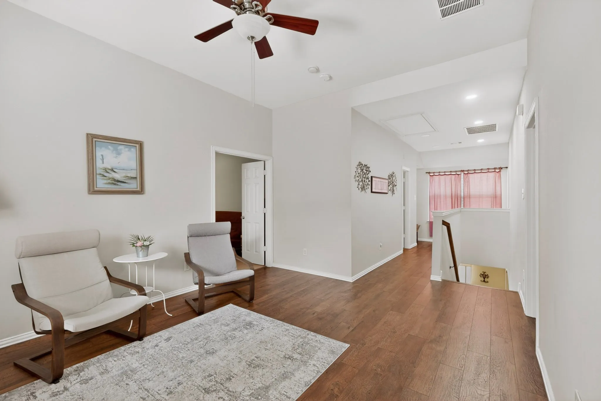 Spacious upper-level landing featuring wood-finish flooring, a vaulted ceiling with a ceiling fan, and recessed lighting