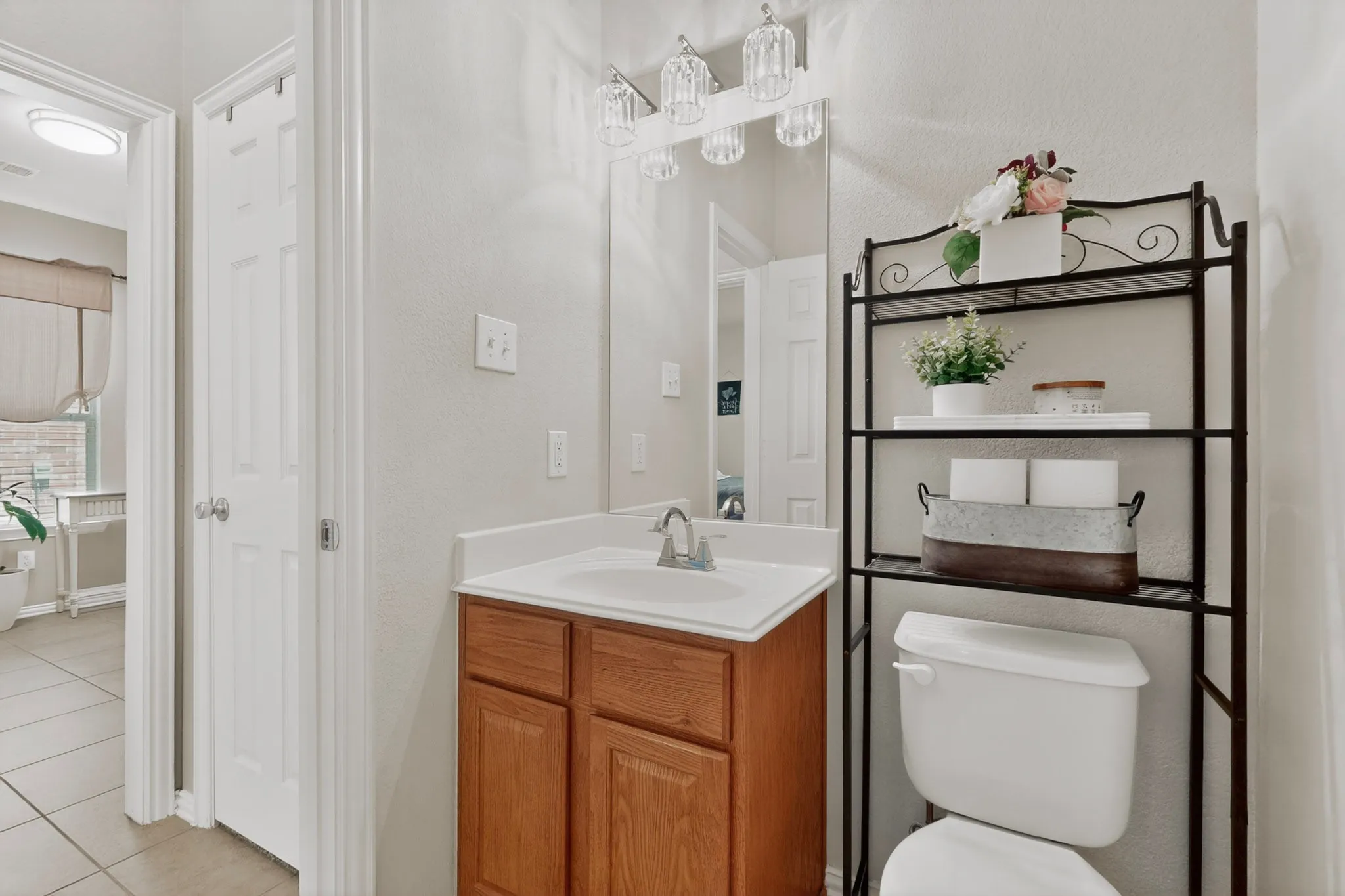 Bathroom featuring a wood-finish vanity with an integrated sink, a large mirror, and a three-light fixture