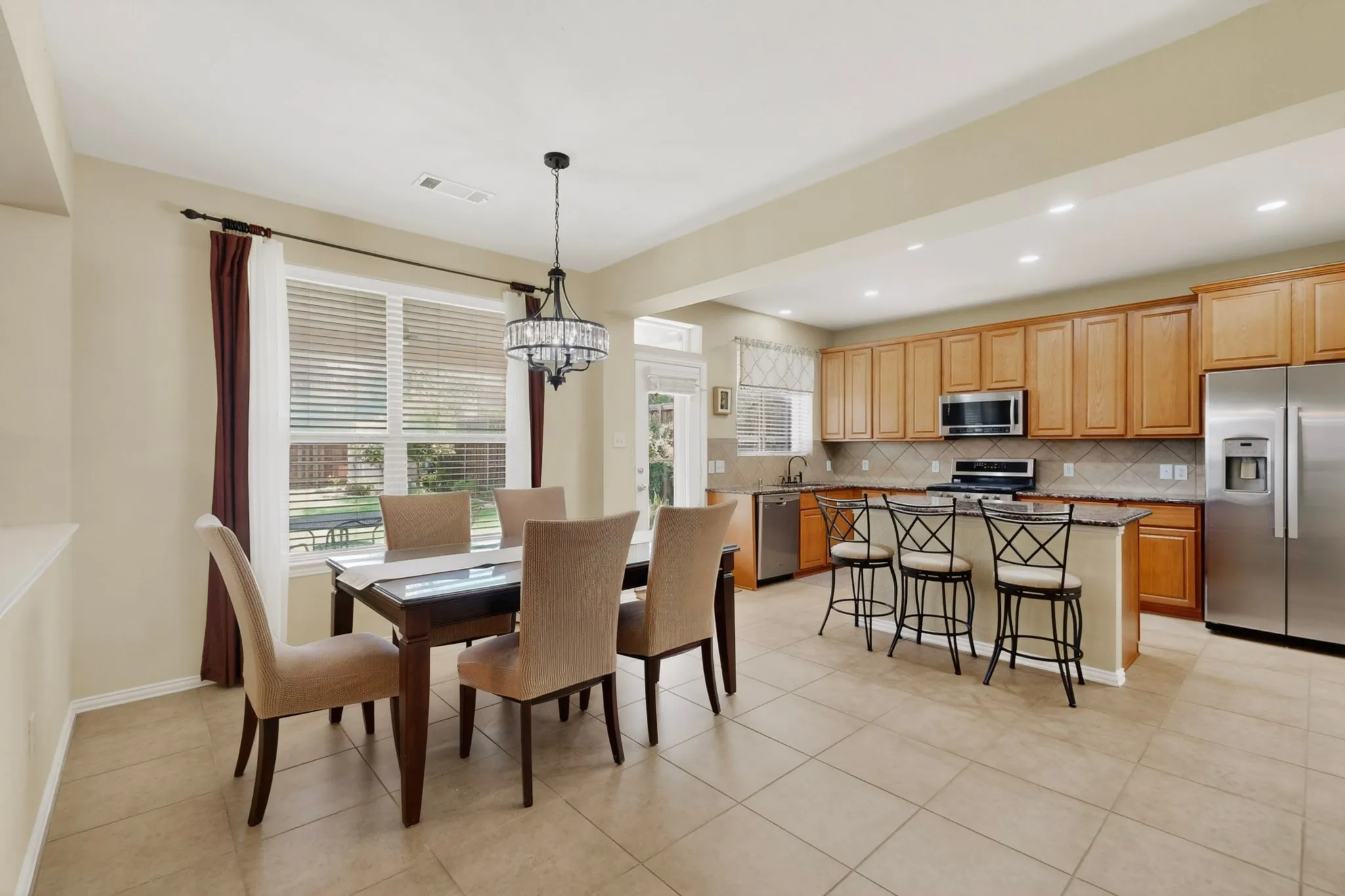 Open-concept kitchen featuring light-toned cabinetry, stainless steel appliances, and a central island with bar seating