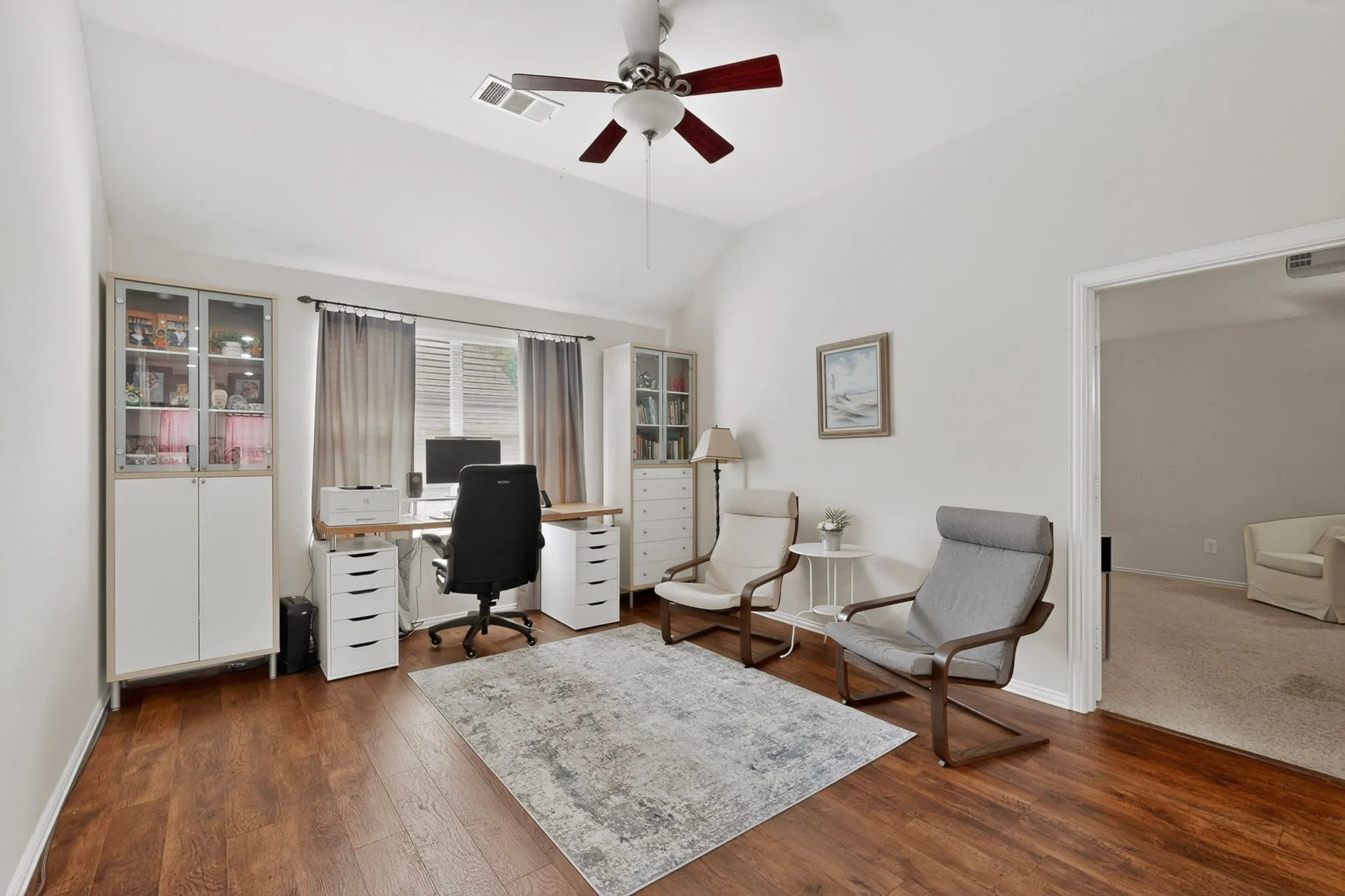 Spacious room featuring vaulted ceilings, wood-finish flooring, and a ceiling fan