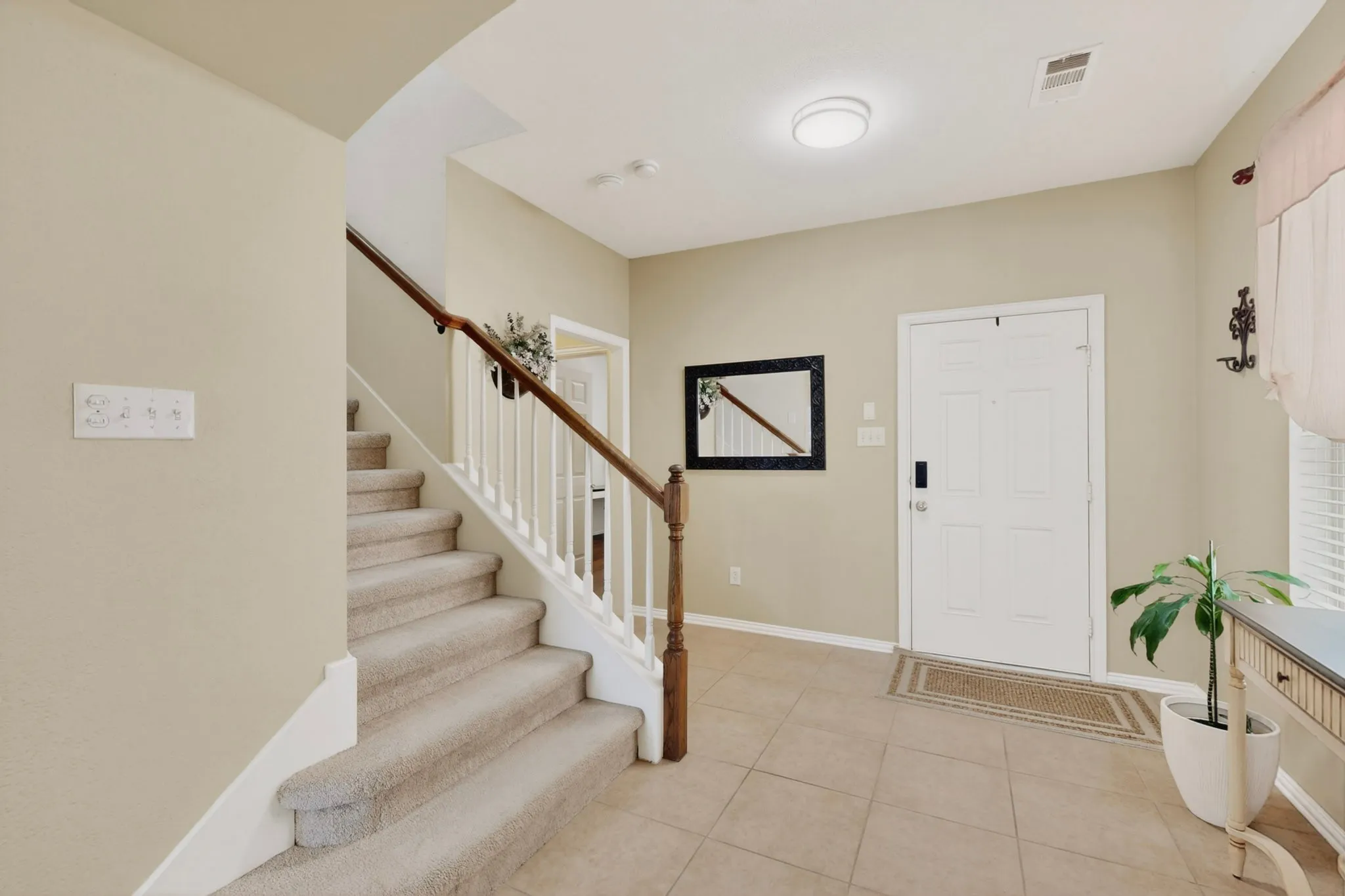 Entryway featuring a paneled front door, ceramic tile flooring, and a carpeted staircase with white balusters and a wood handrail