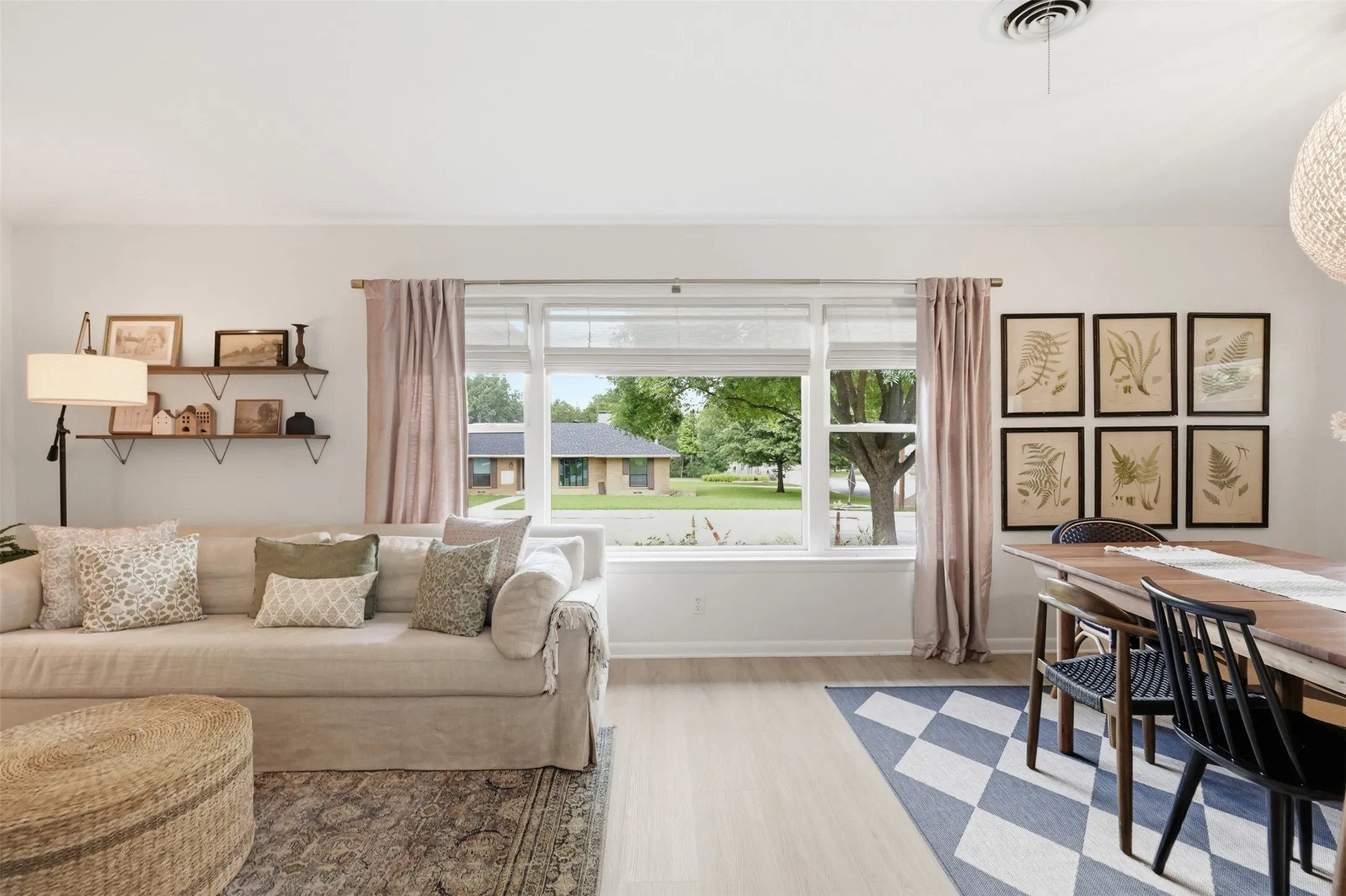The oversized window separates the dining room and living room space and adds lots of natural light.  Custom shades cover the windows when needed but still allow natural light to seep through.