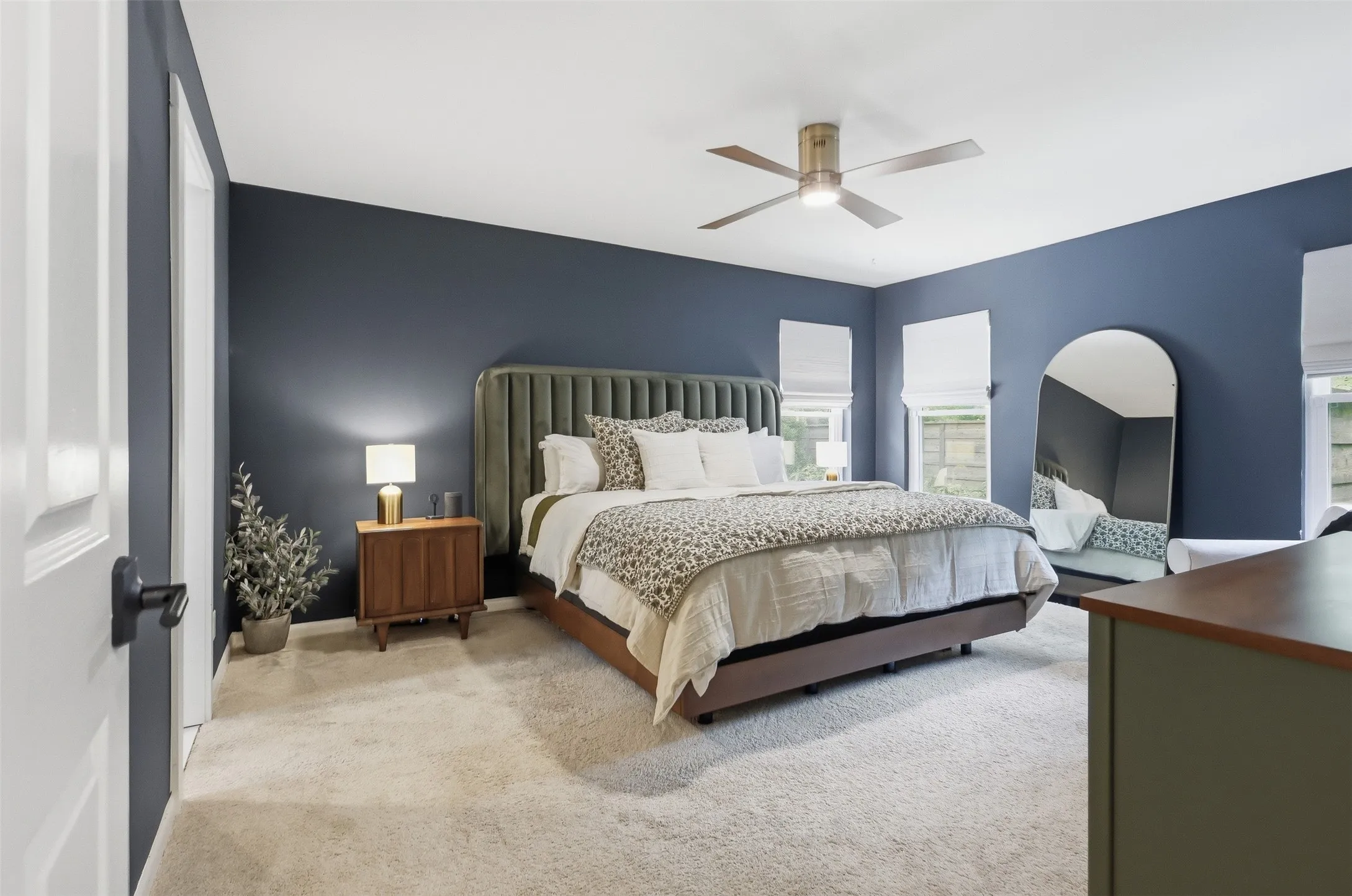 Large Primary Bedroom with custom shades on windows, new ceiling fan and inviting paint color.