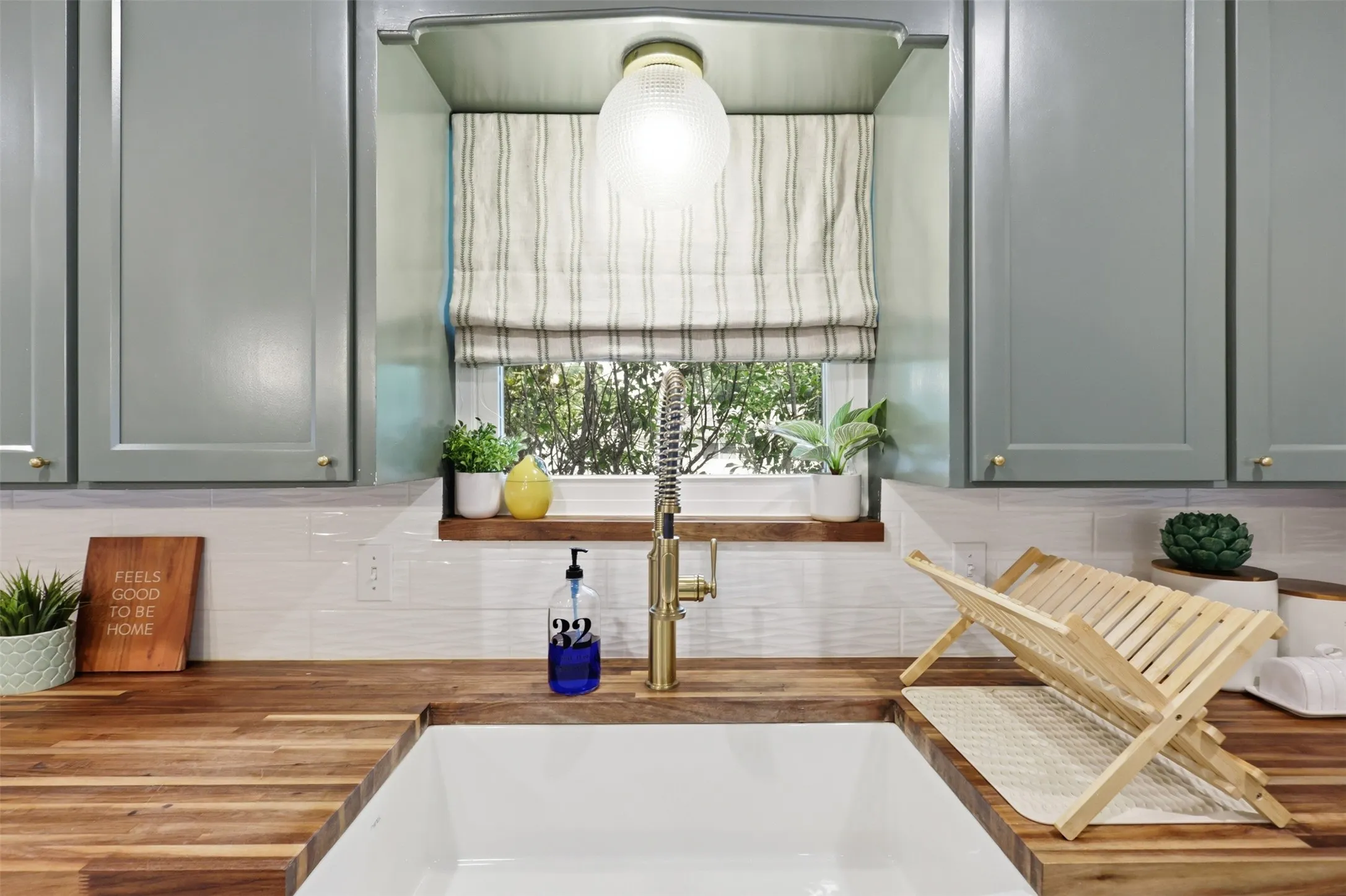 Farmhouse sink with charming kitchen window and custom shade.