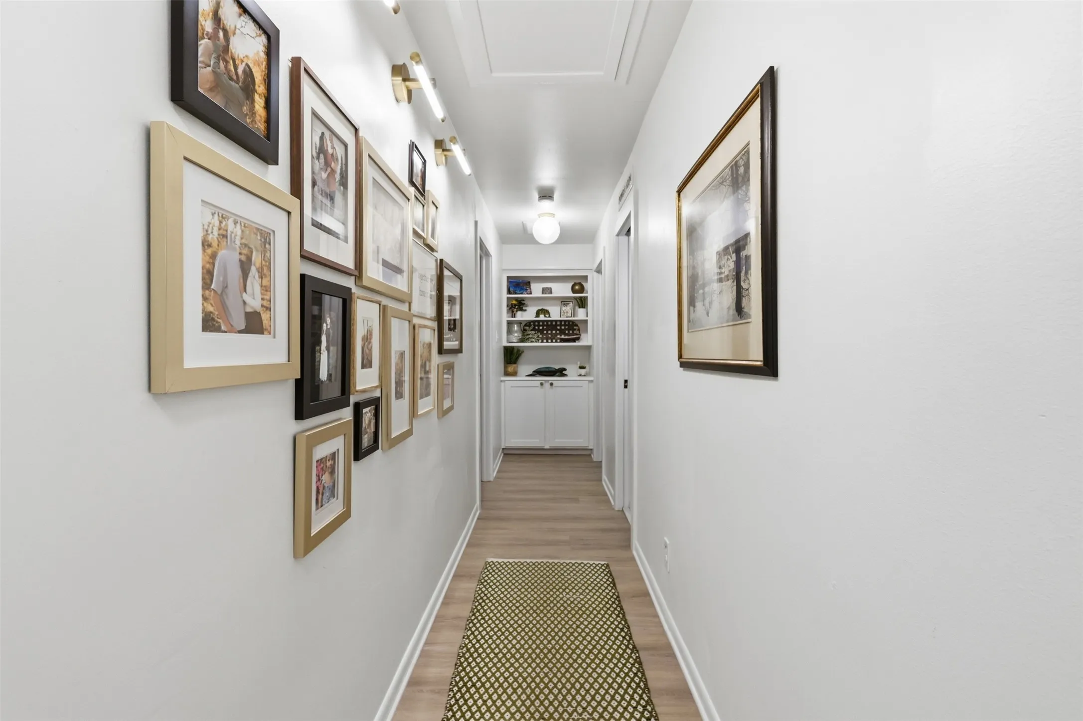 Hallway leading to the bedrooms with built ins and hard wired lighting for portrait gallery wall.