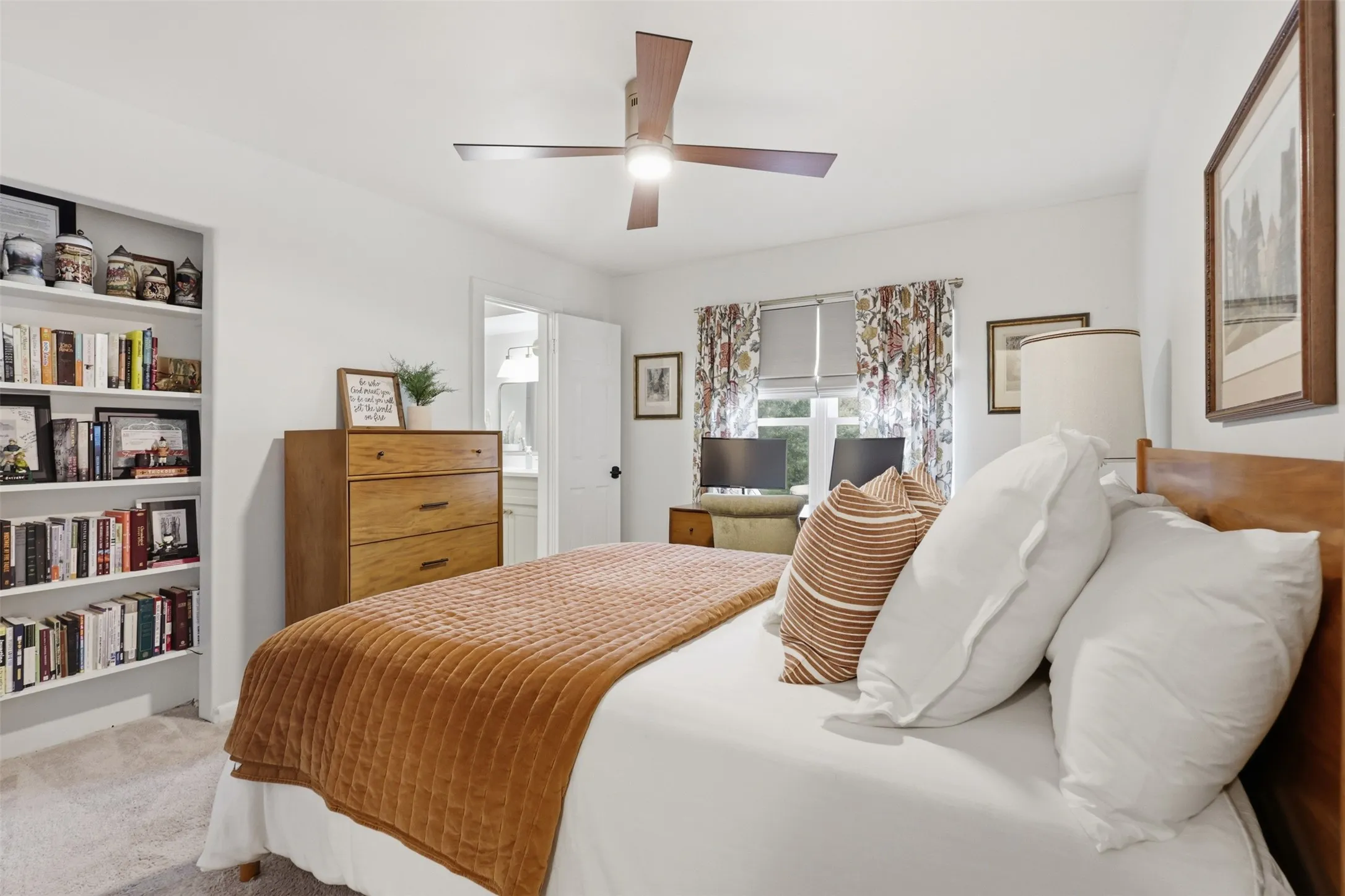 Secondary Bedroom with Built In Bookshelves and Large Window.  Custom Shades and New Ceiling Fan round out the room.