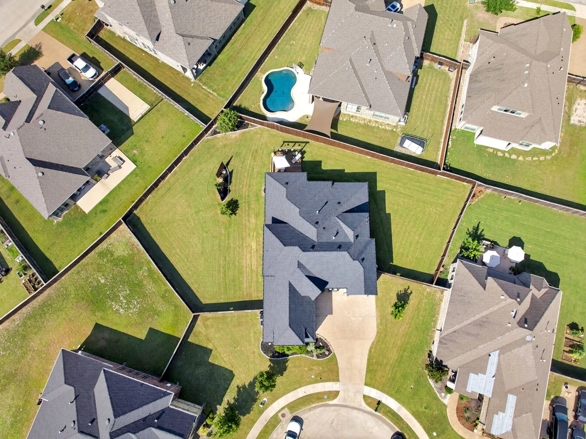 Aerial perspective highlighting a residential property with a multi-pitched dark gray roof