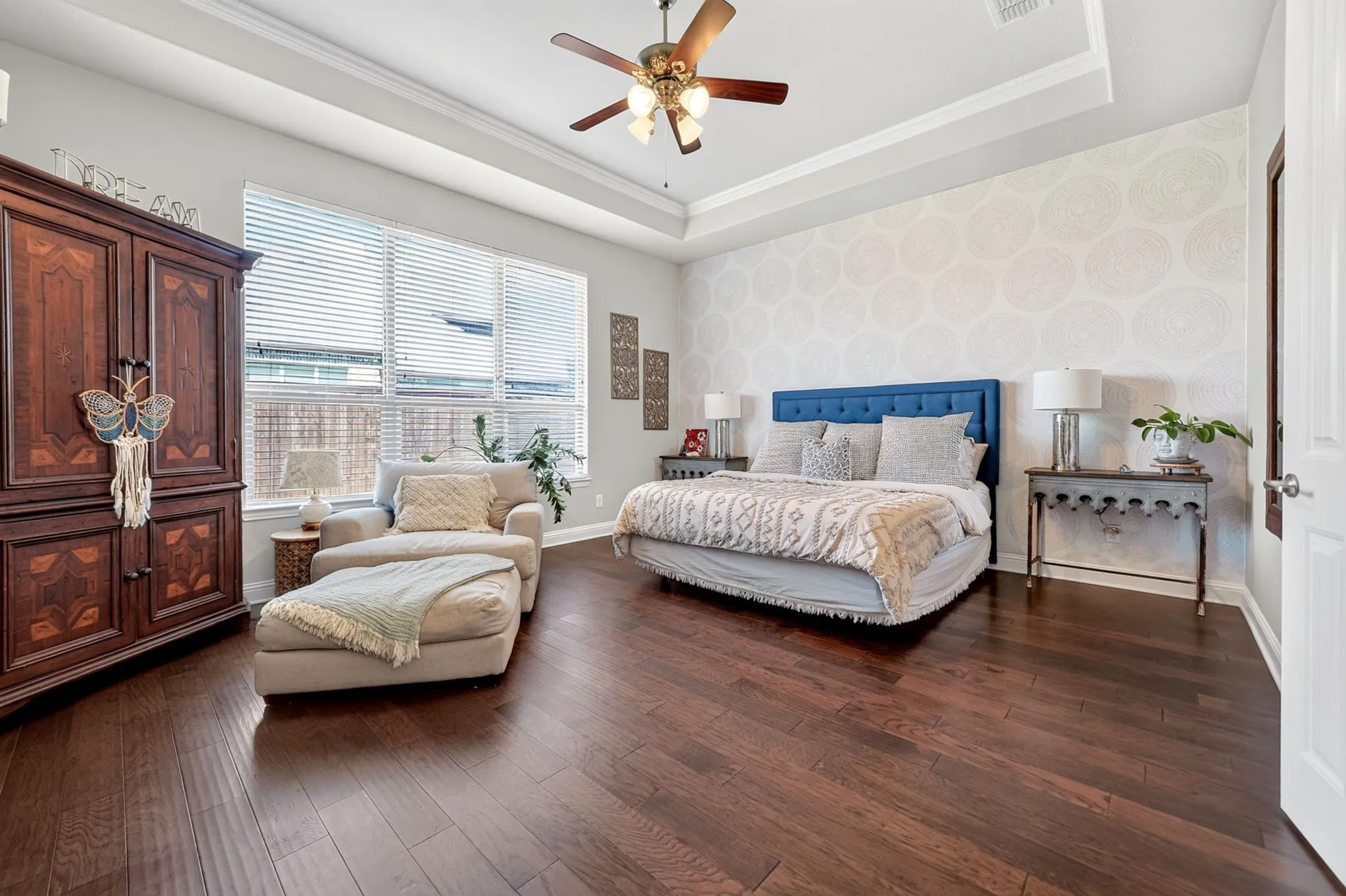 Spacious room featuring rich wood-finish flooring and a tray ceiling with a built-in ceiling fan