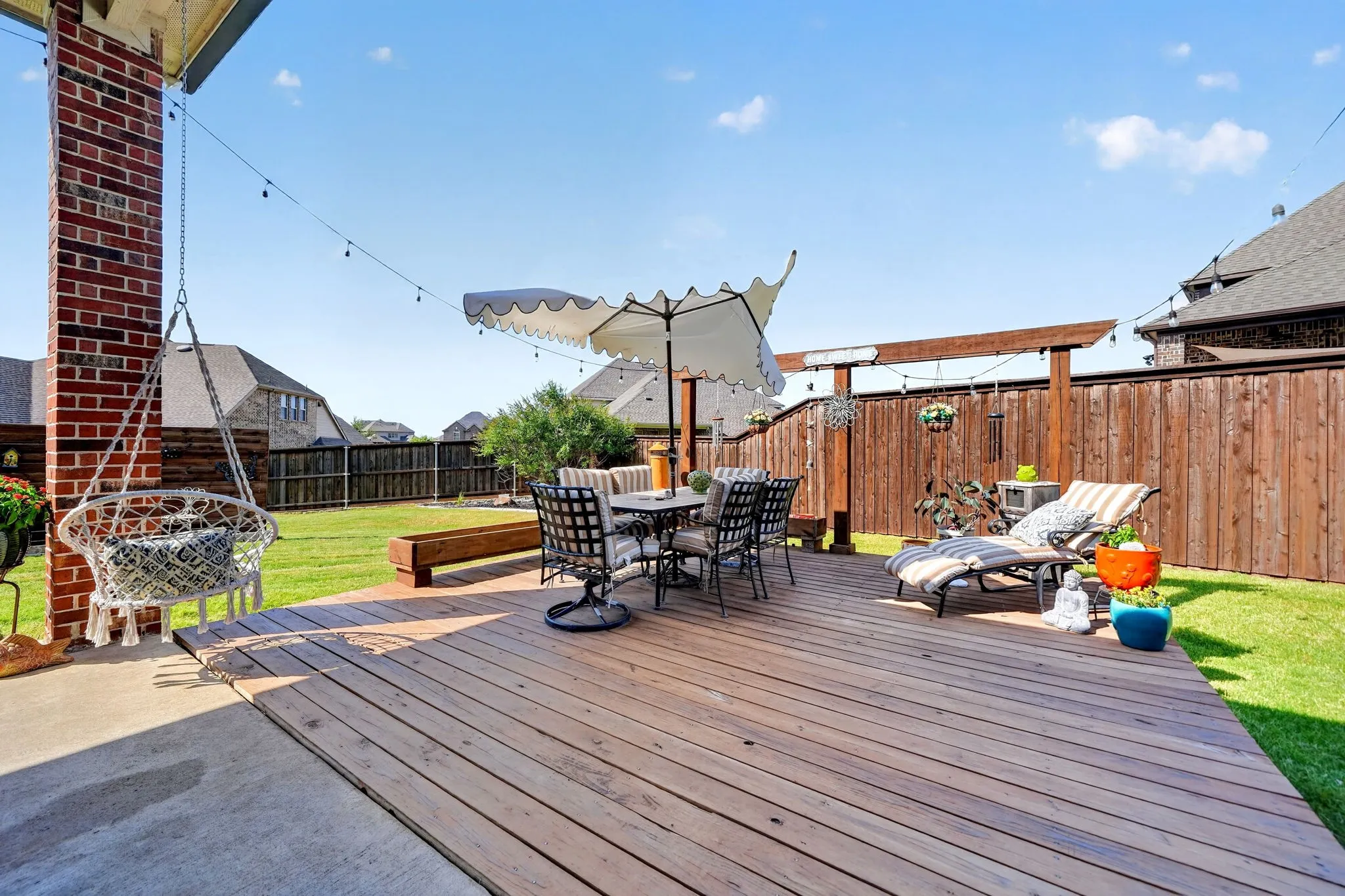 Expansive wood-finish deck complemented by a brick column and string lighting