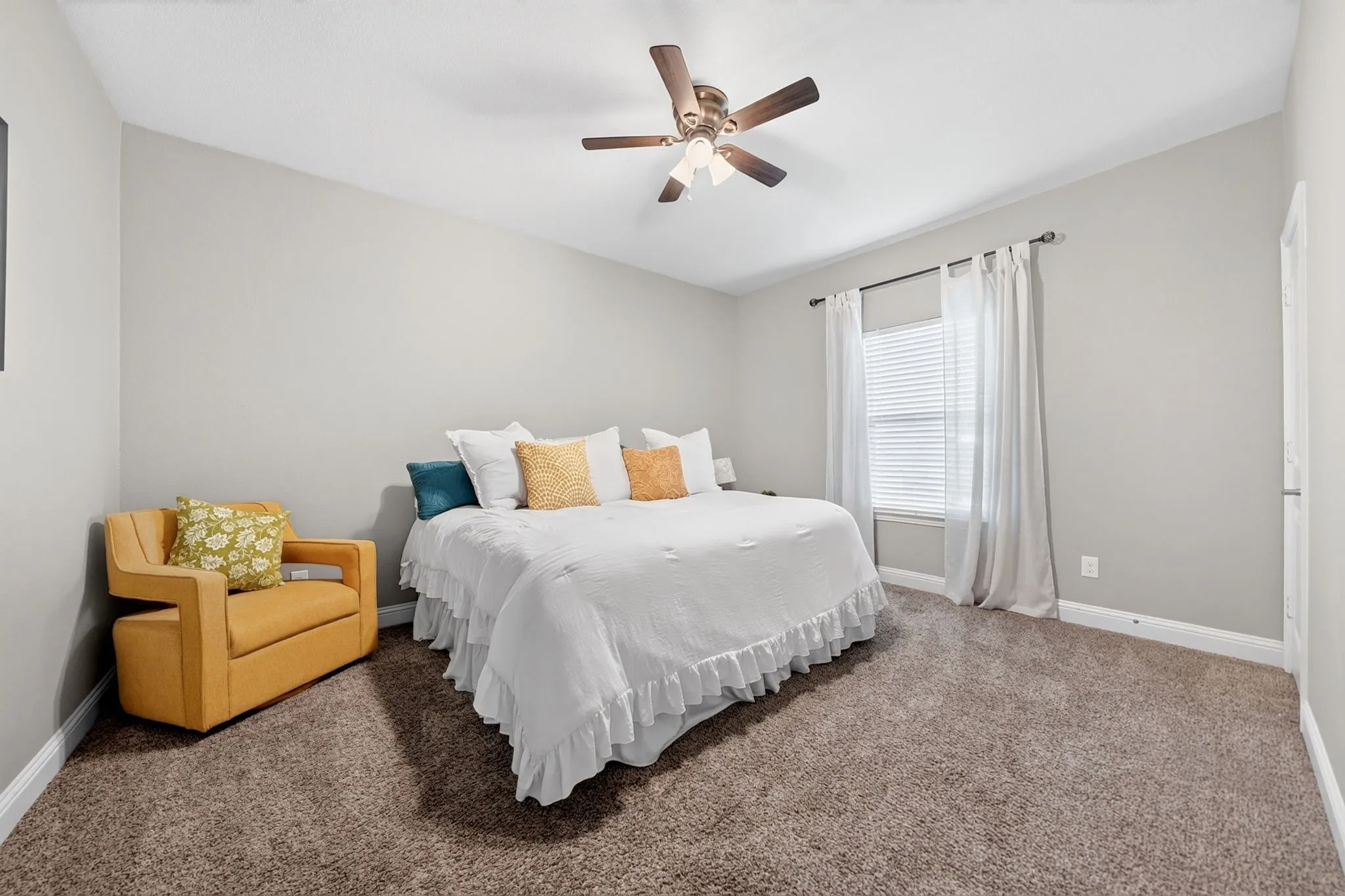 Carpeted room with a ceiling fan, window with blinds and curtains, and light gray walls