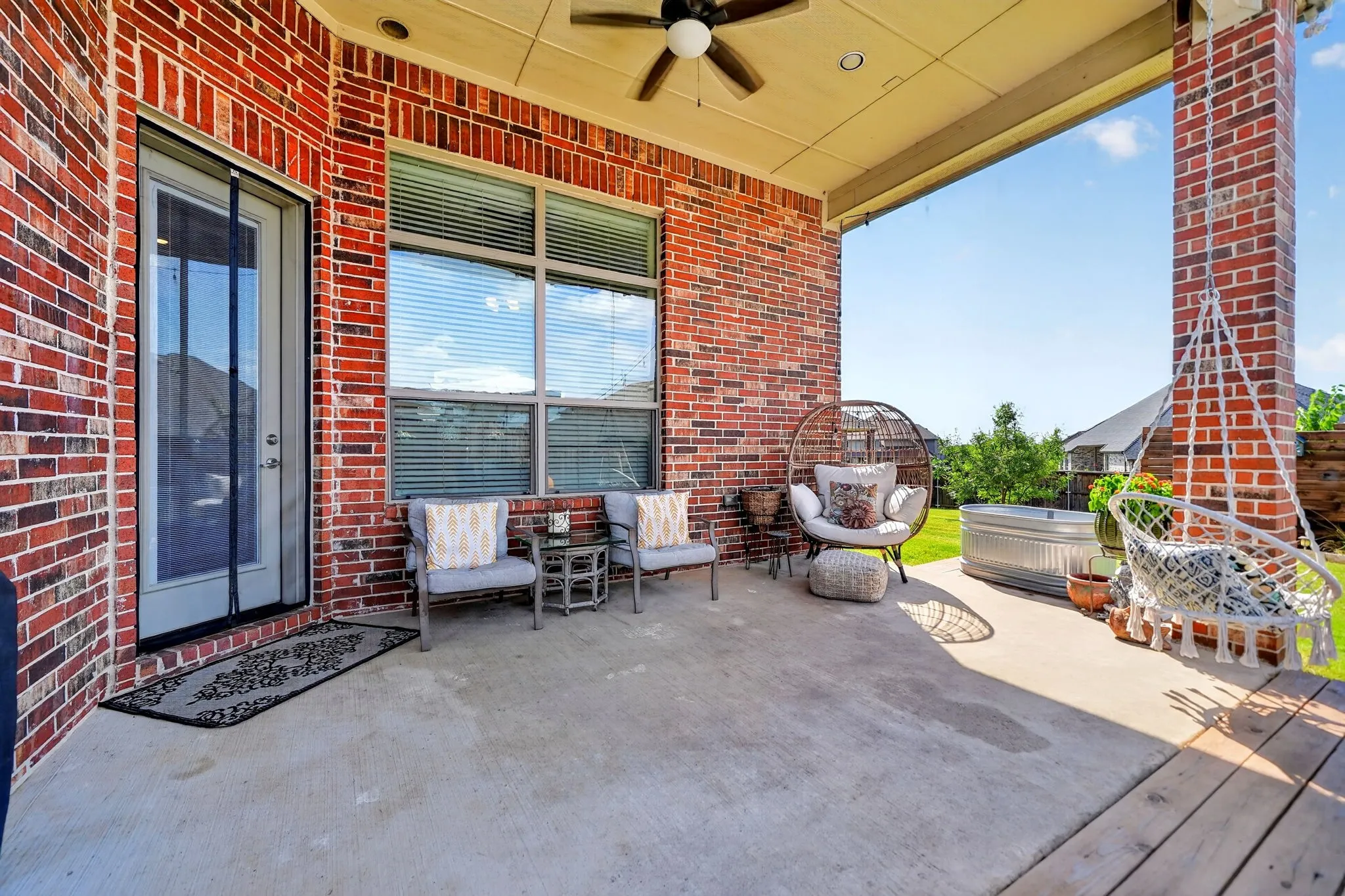 Covered outdoor patio with exposed brick columns, a ceiling fan, and recessed lighting