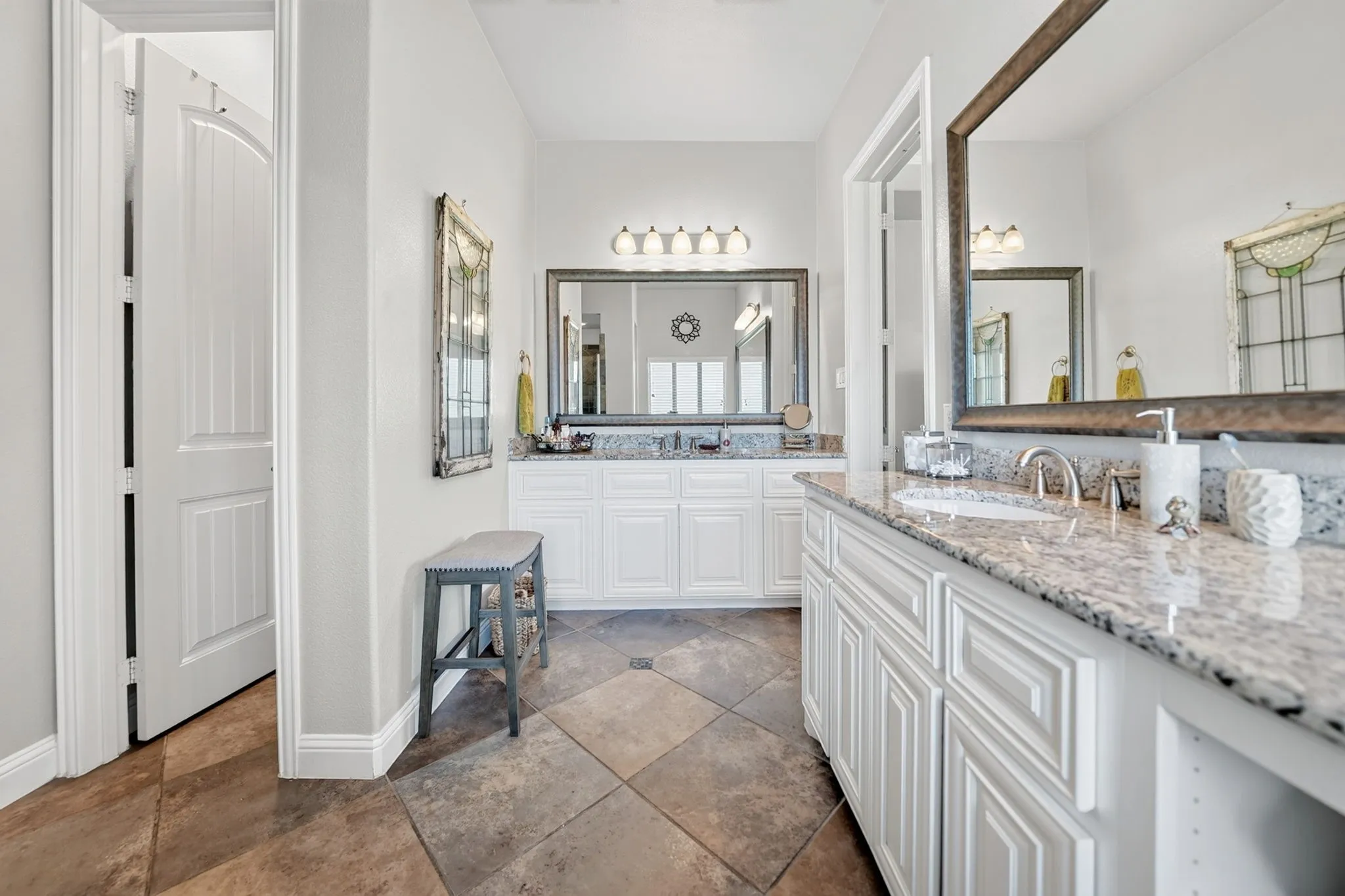 Double vanity with light granite countertops, white cabinetry, and undermount sinks