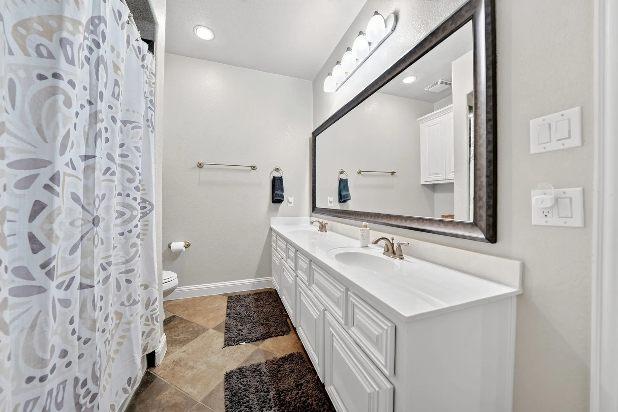 Dual vanity featuring integrated sinks, white cabinetry, and brushed nickel fixtures