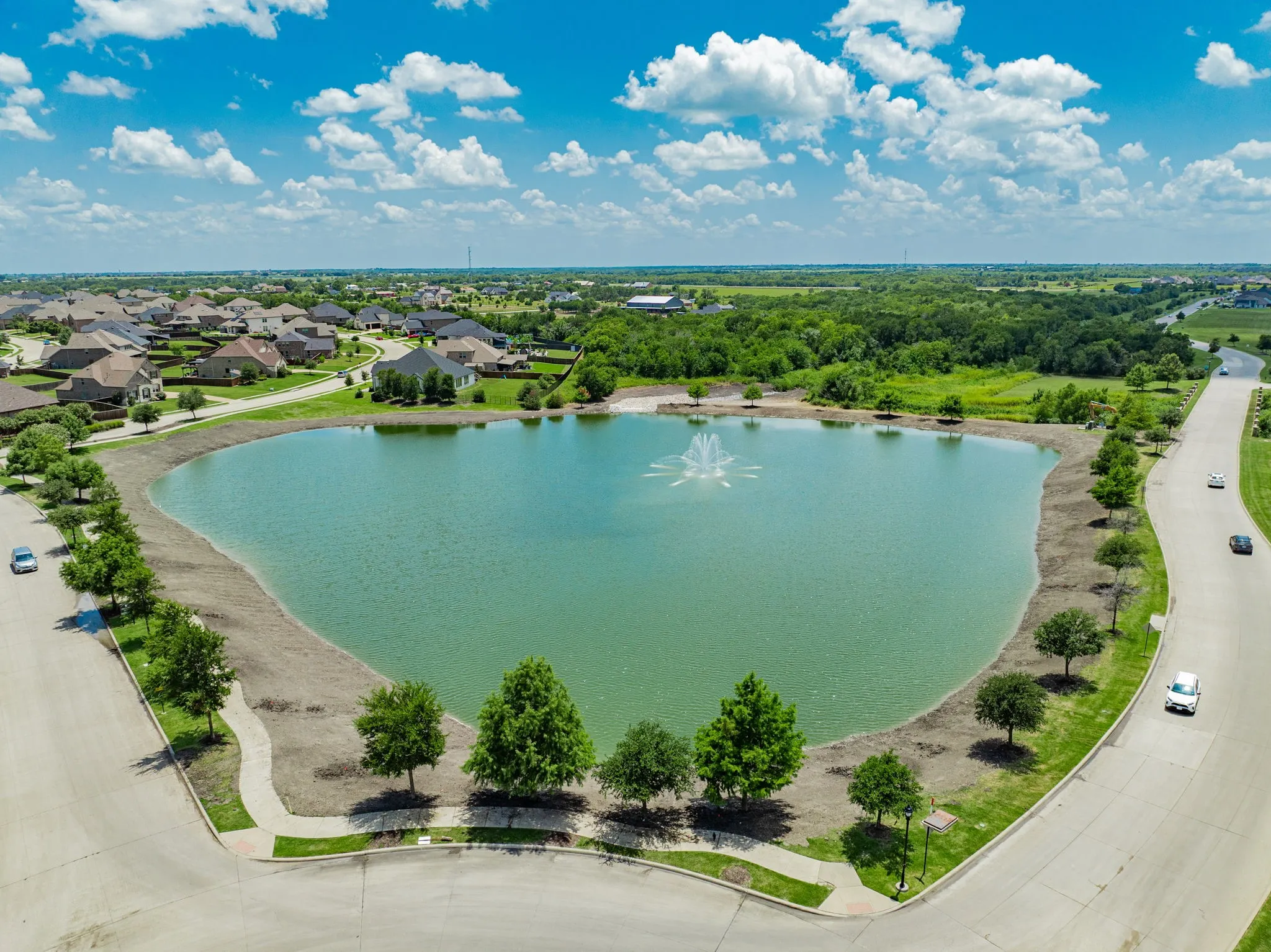 Community lake featuring a central fountain and surrounding green spaces