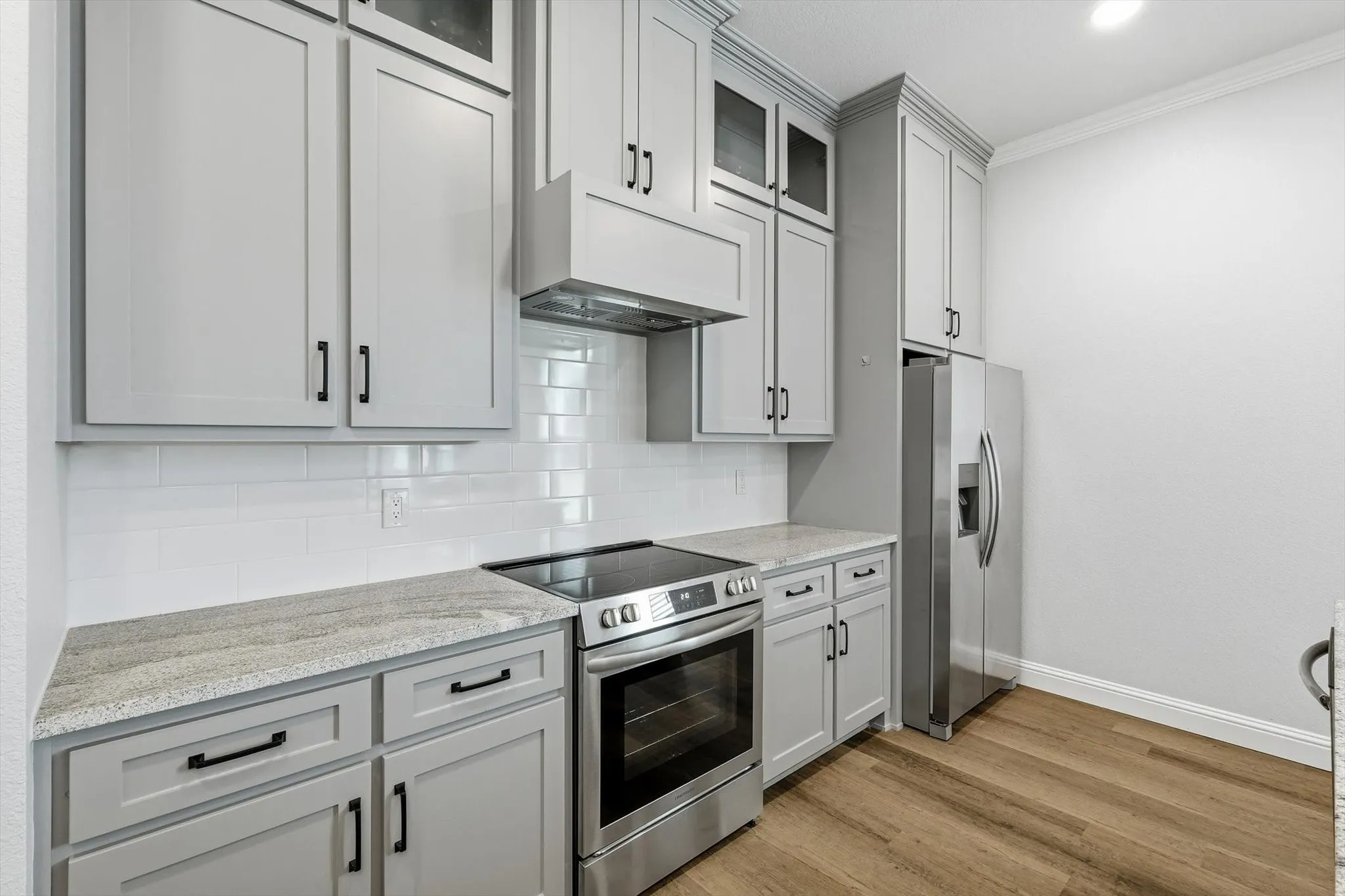 Guest Home - Kitchen featuring light gray shaker cabinetry, stainless steel appliances, a white subway tile backsplash, and light-toned countertops