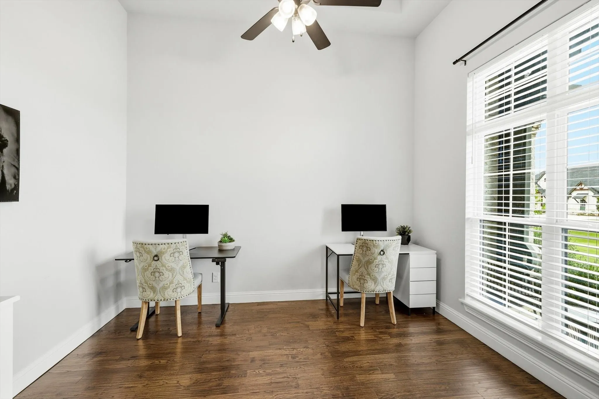 Hardwood flooring throughout featuring high ceilings, a ceiling fan, and large windows with horizontal blinds