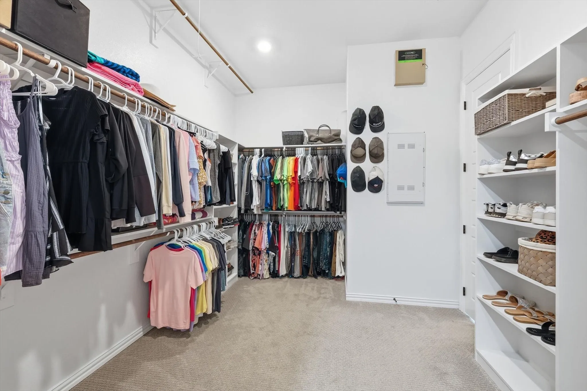Spacious walk-in closet featuring light-colored carpeting, white walls, and recessed lighting