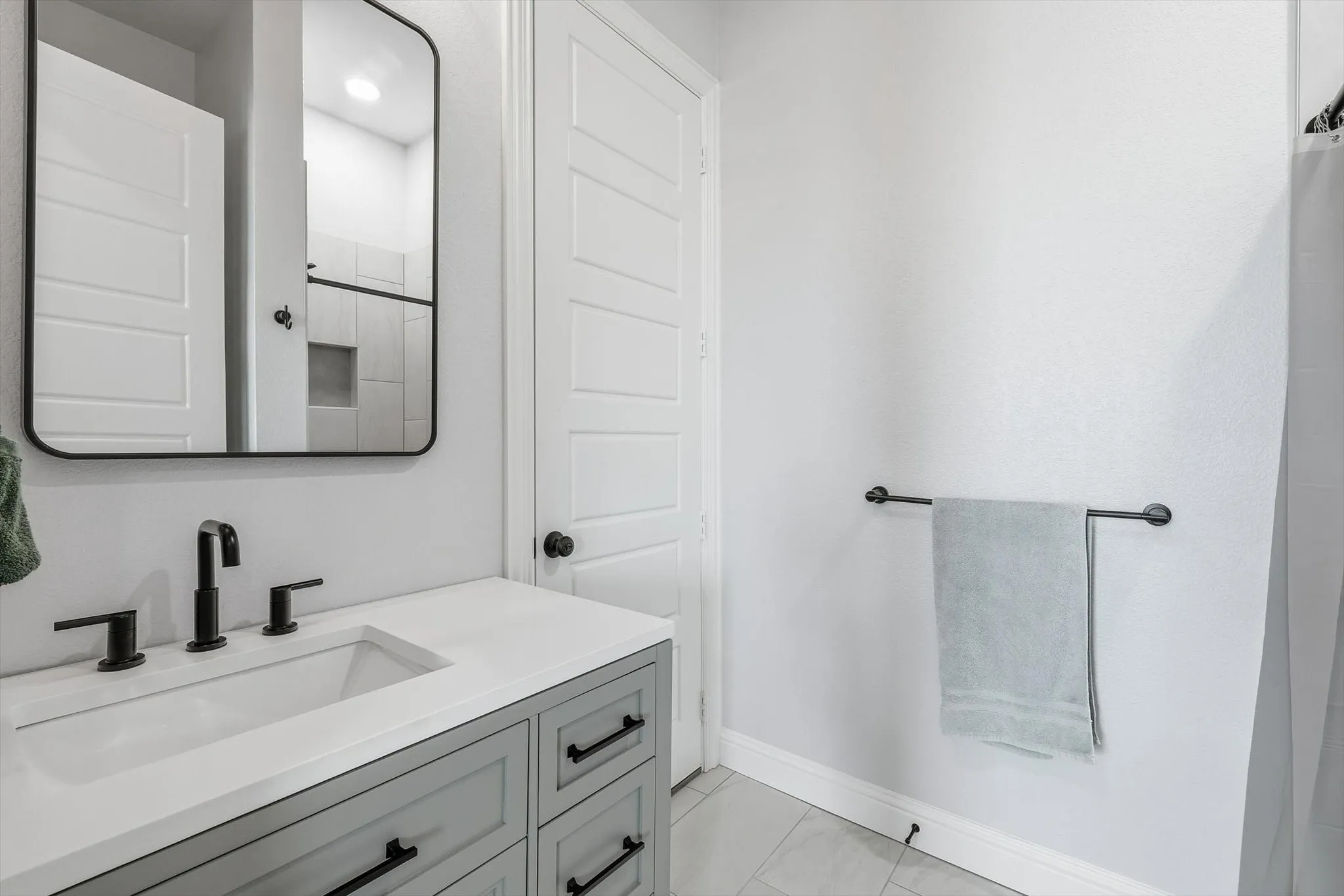 Guest Home (1 of 2 bathrooms) - Bathroom vanity featuring a white rectangular undermount sink, matte black faucet, and light gray cabinetry with black hardware