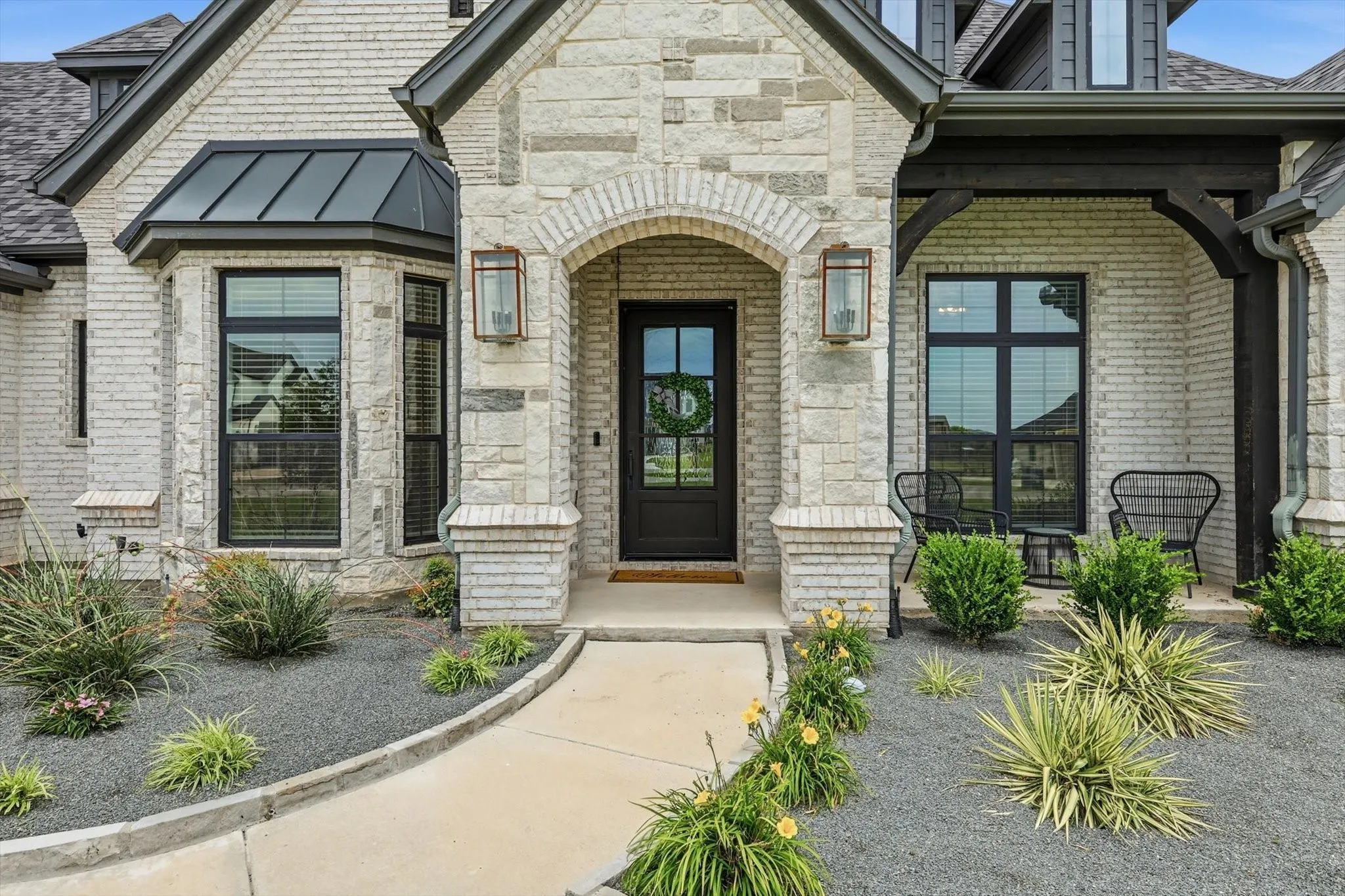 Main Home - Stone and brick exterior with dark trim accents and a black front door